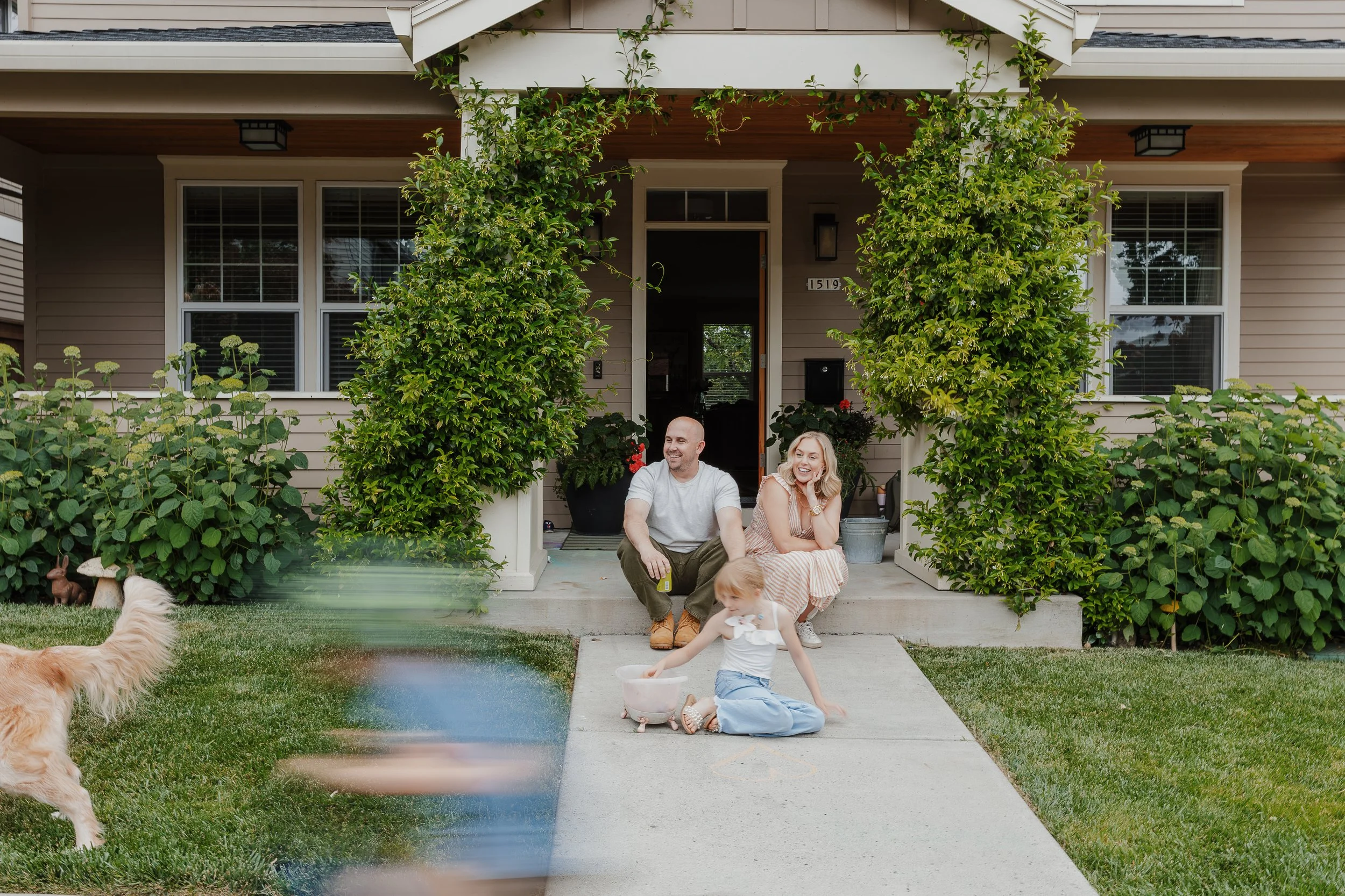 Family sits in front of house and plays during an in-home family photo session in Raleigh, NC.