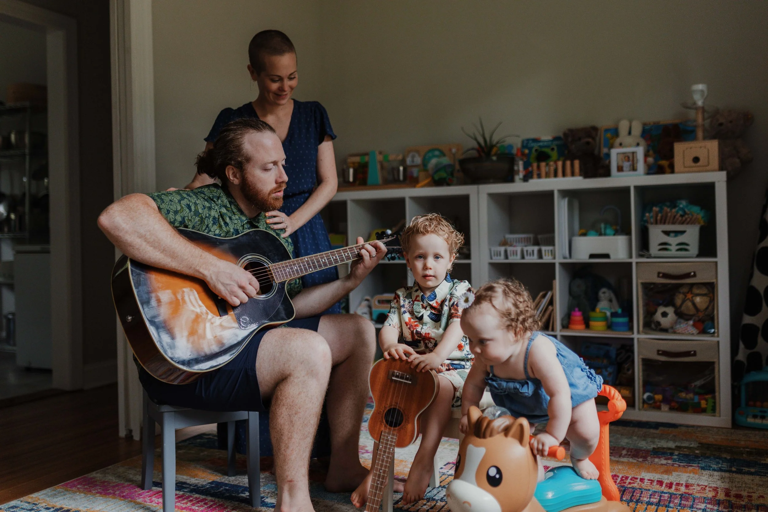 Family with two young kids plays music together during professional lifestyle family photo session at home in Wake Forest, NC.