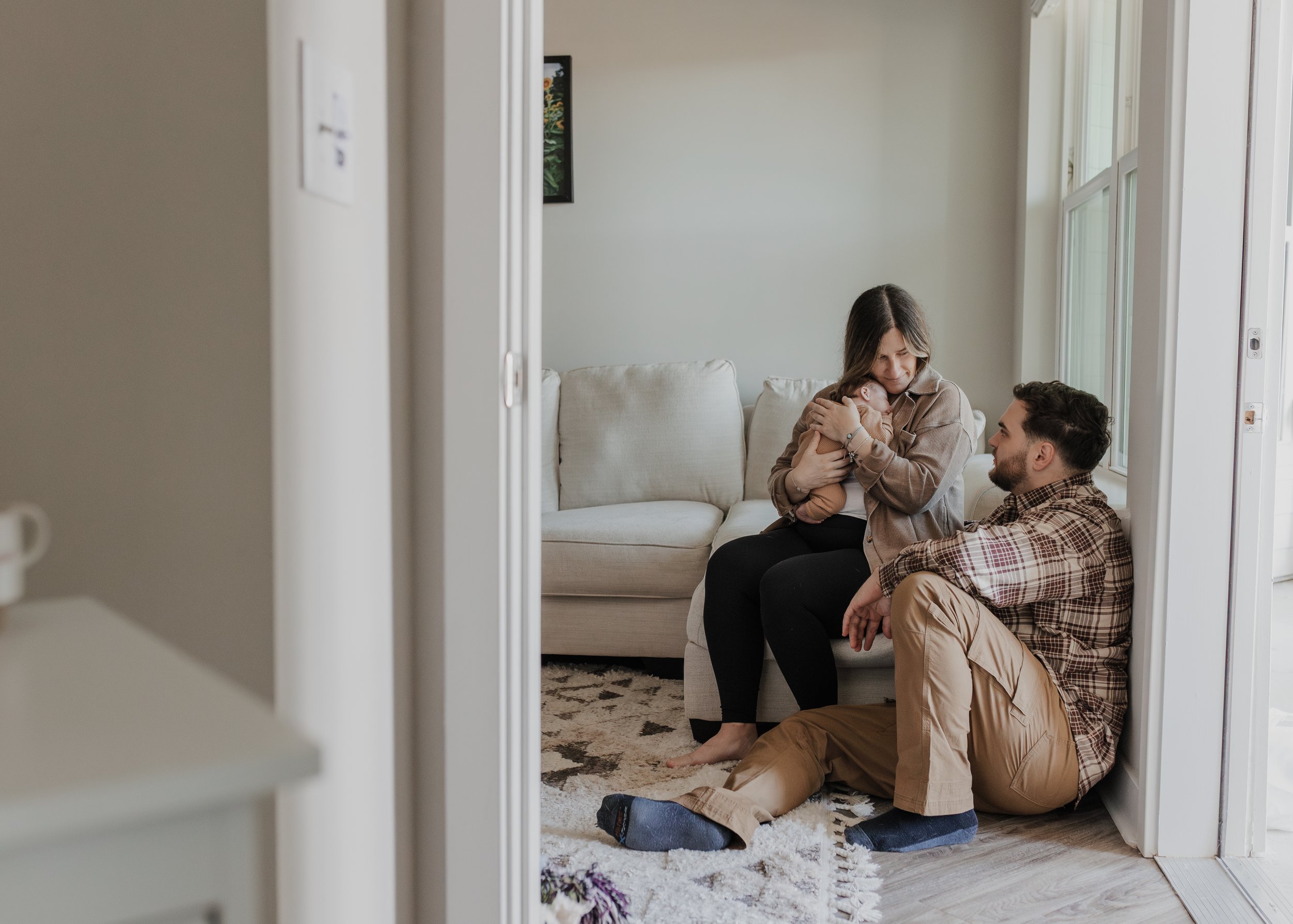 Mom and dad hold baby in living room during an at-home newborn photoshoot in Raleigh, NC.