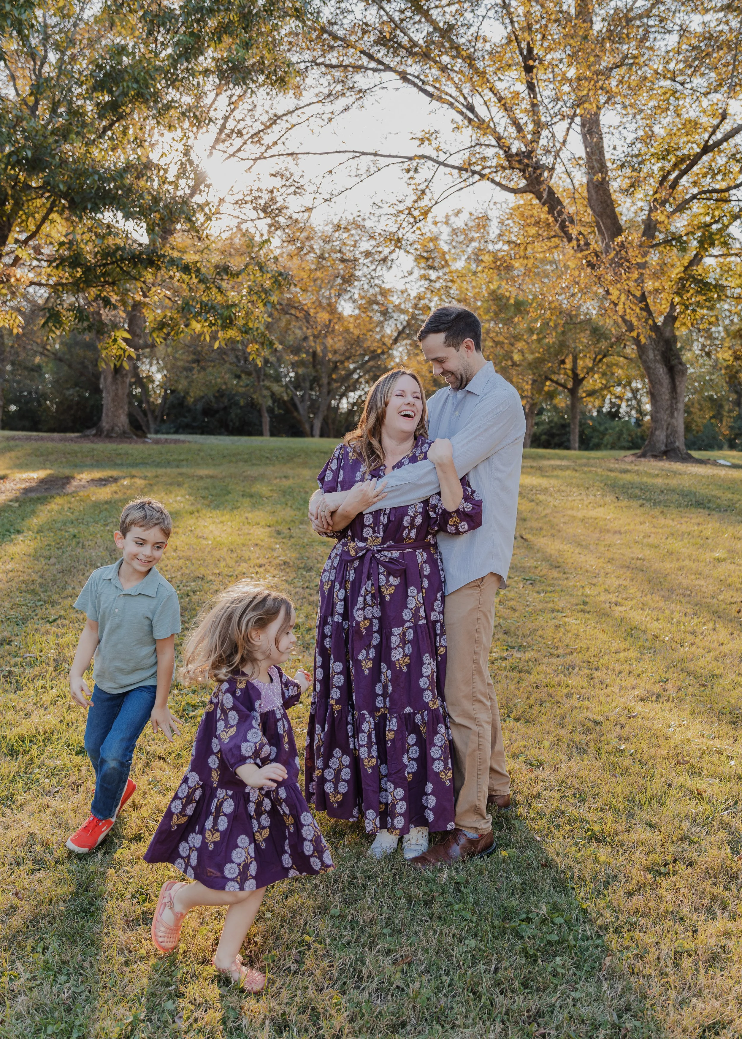 Mom and dad laugh together while kids run around them beneath the pecan trees at Historic Oak View County Park.