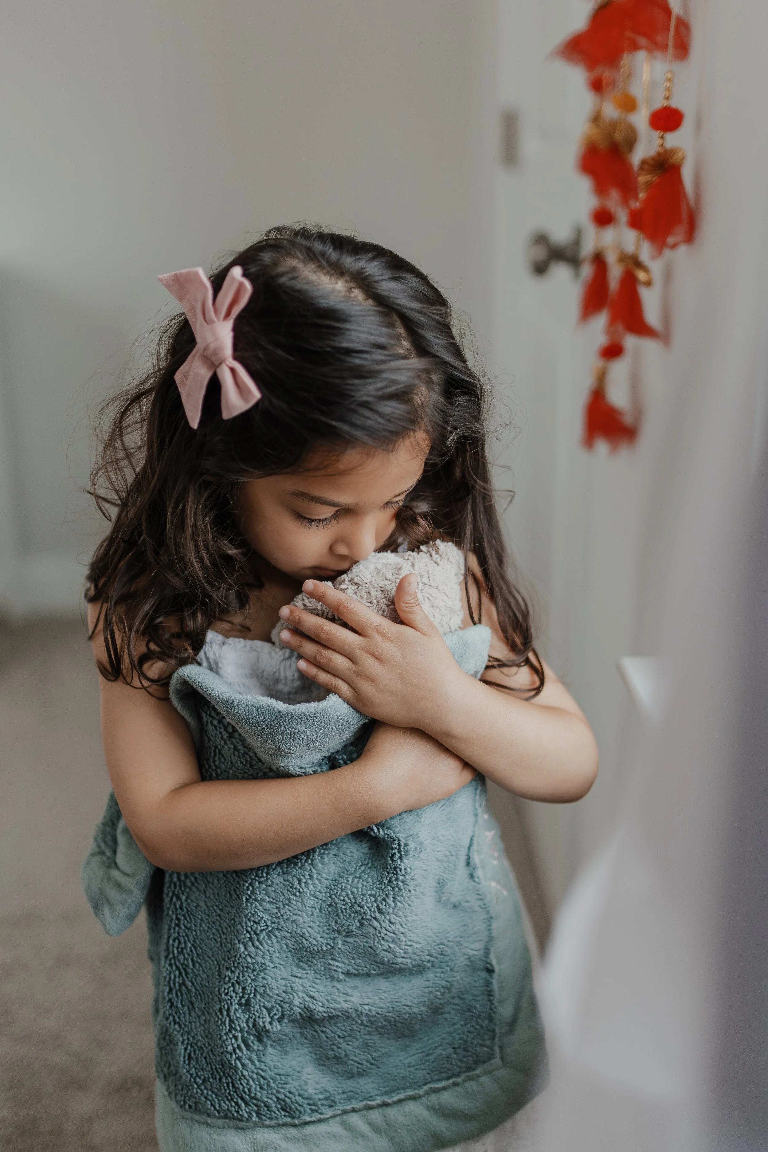 Toddler holds stuffed animal like a baby during an in-home newborn photo session in Durham, NC.