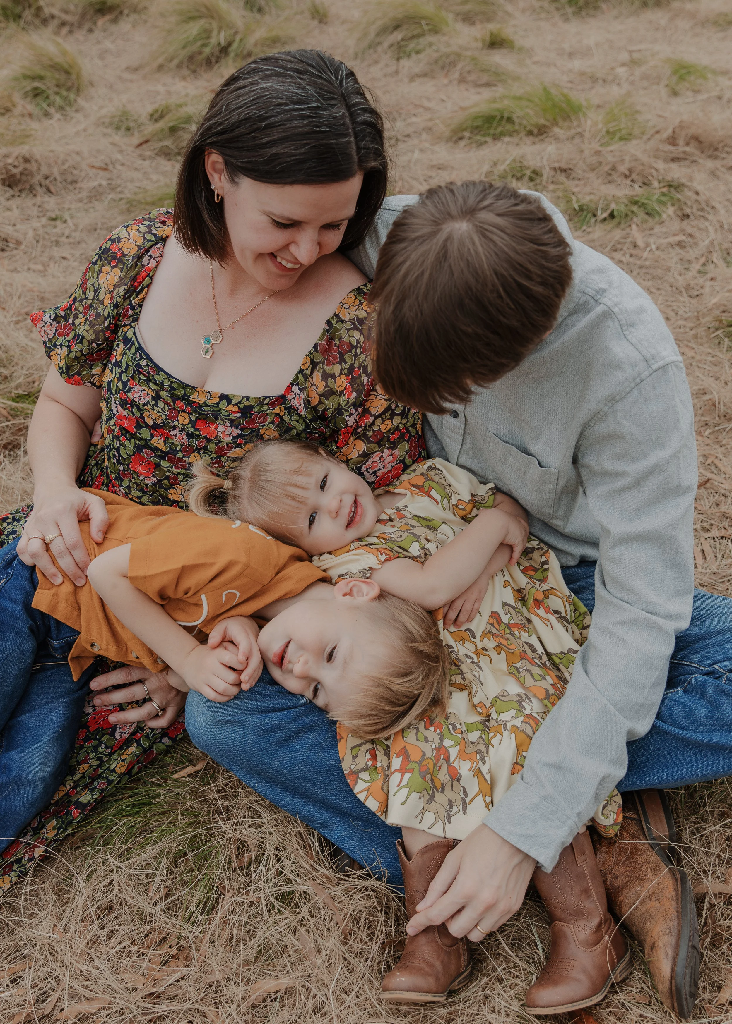Family sits on ground with young children during a fall mini session at North Carolina Museum of Art Park in Raleigh.