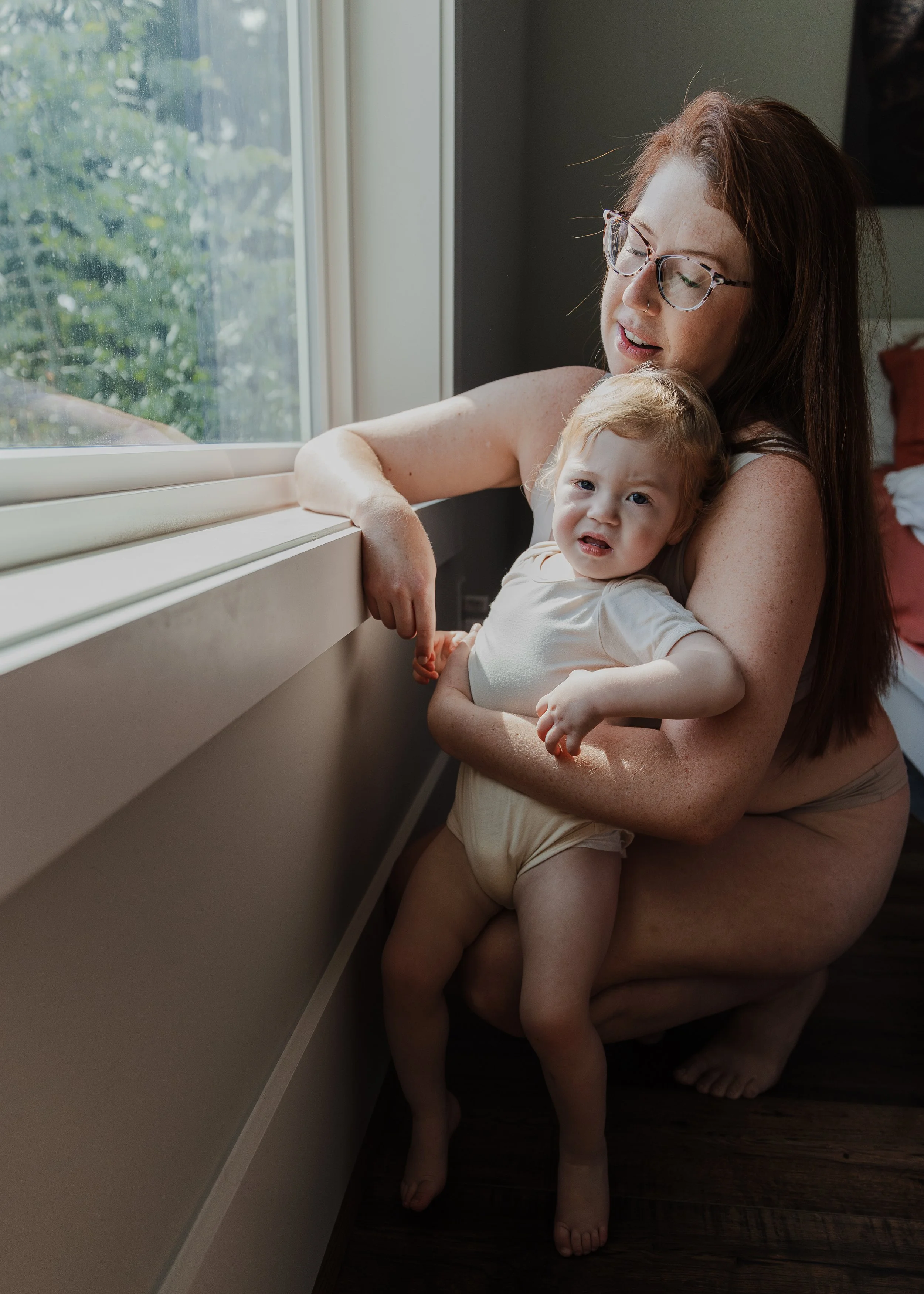 Toddler cries while mom holds her during a professional motherhood photoshoot at home in Raleigh, NC.