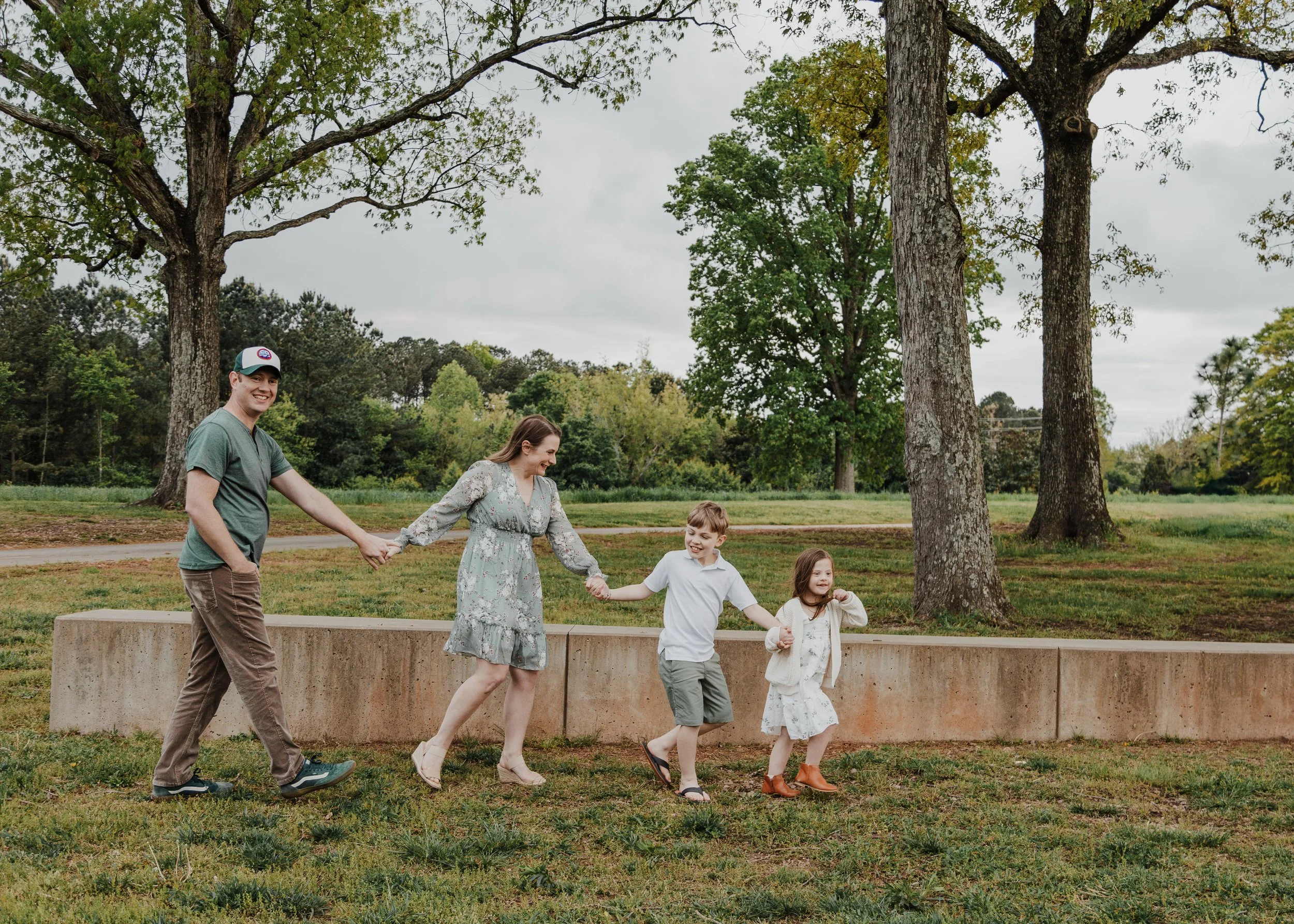 Family walks hand-in-hand at the North Carolina Museum of Art during a spring mini photosession.