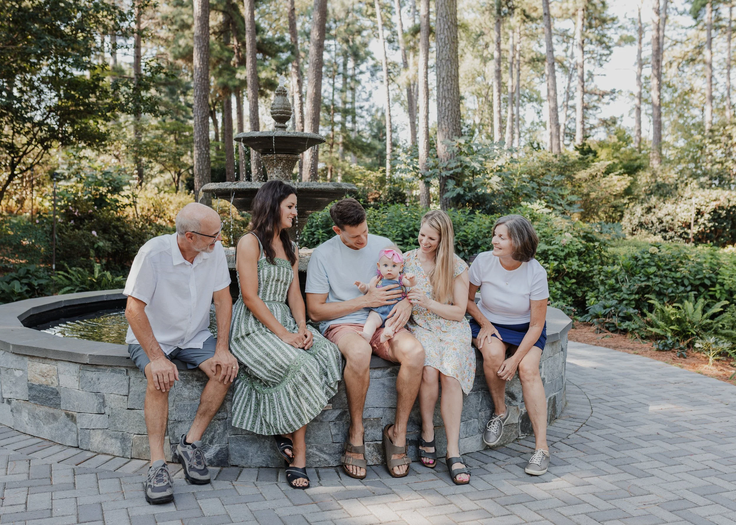 Extended family sits together on the fountain at the WRAL Azalea Gardens during spring time.