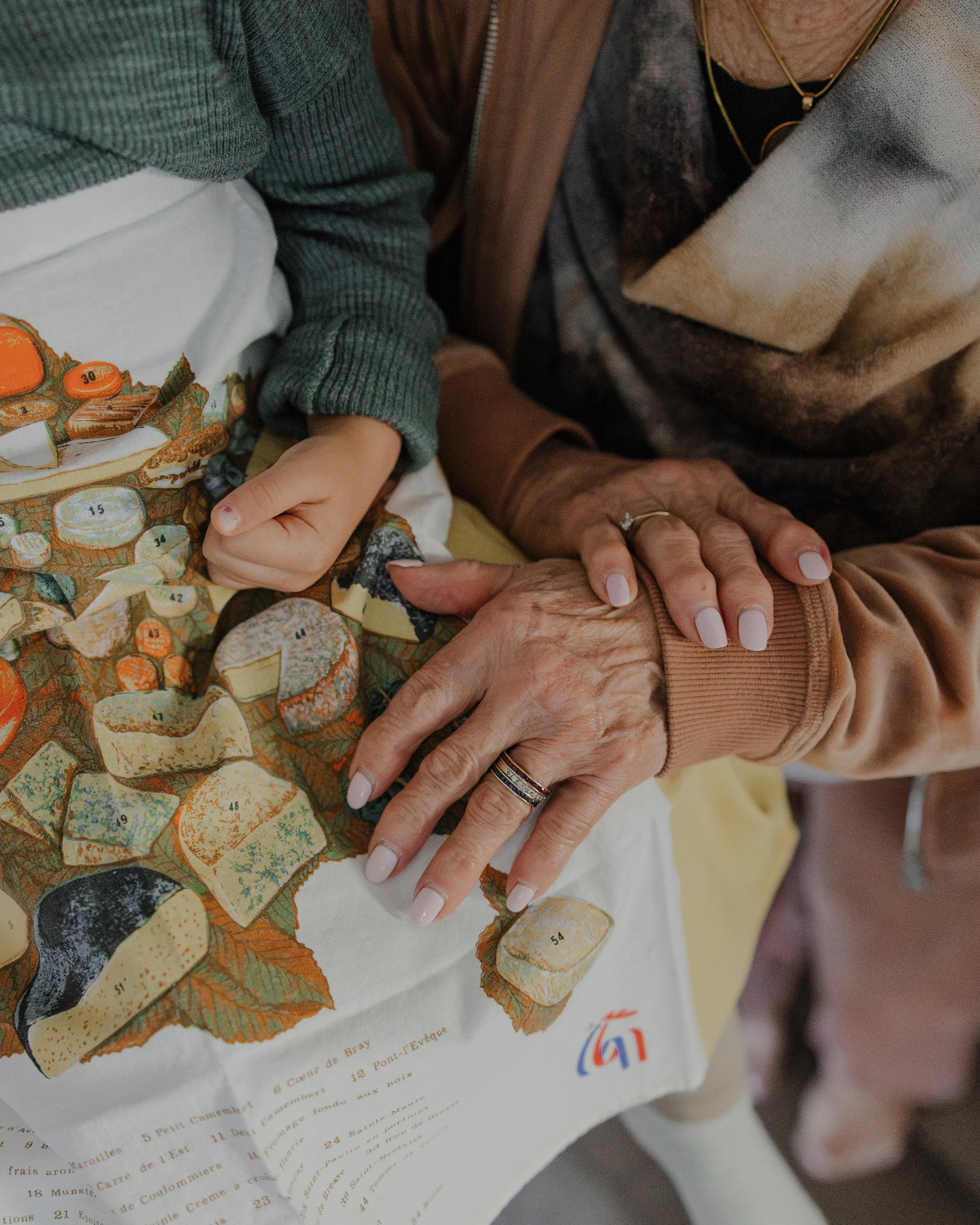 Close-up of grandmother’s hands resting over a child’s lap during a multi-generational family photo session in Chapel Hill.