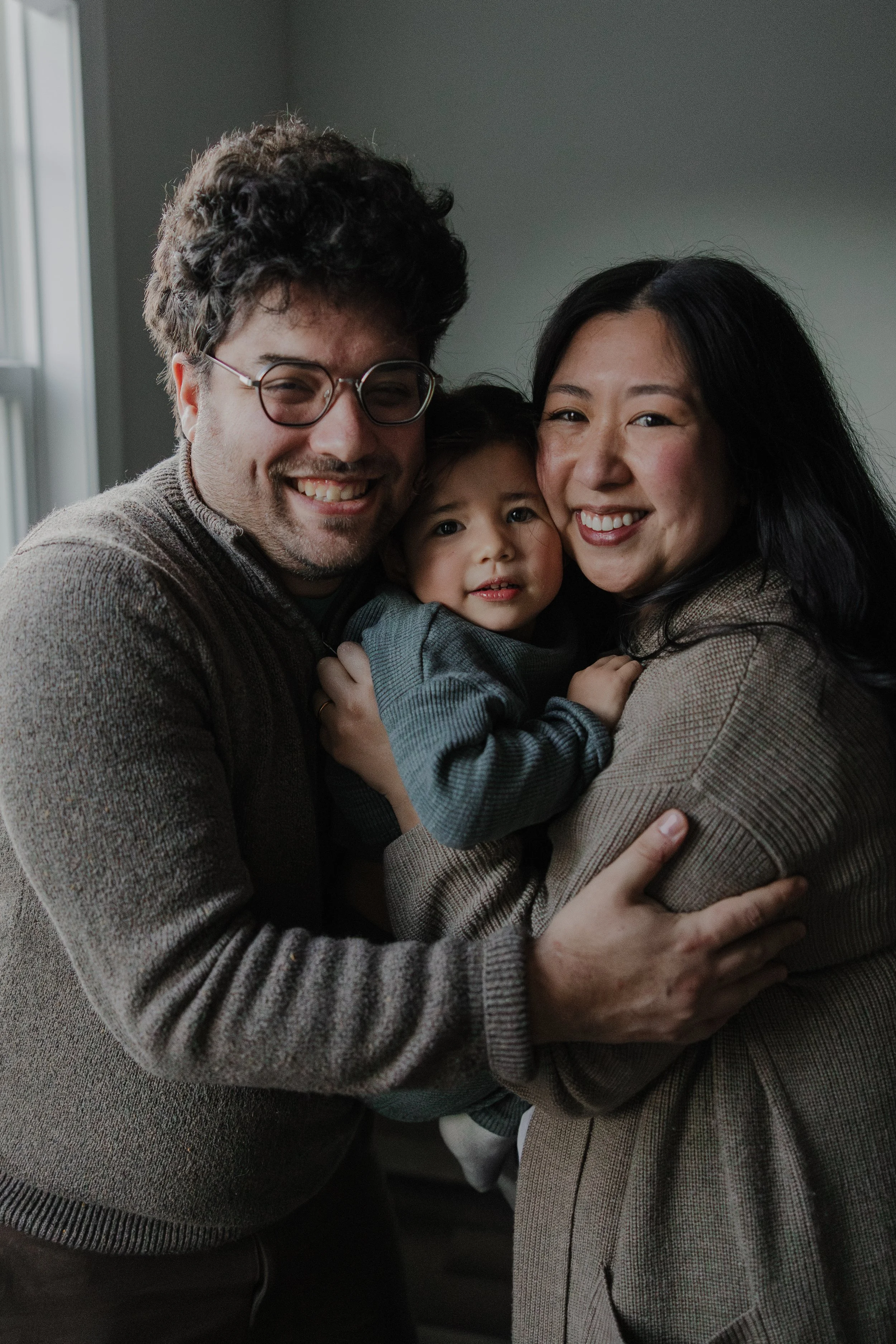 Parents embracing their toddler during an at-home family photo session in Chapel Hill.