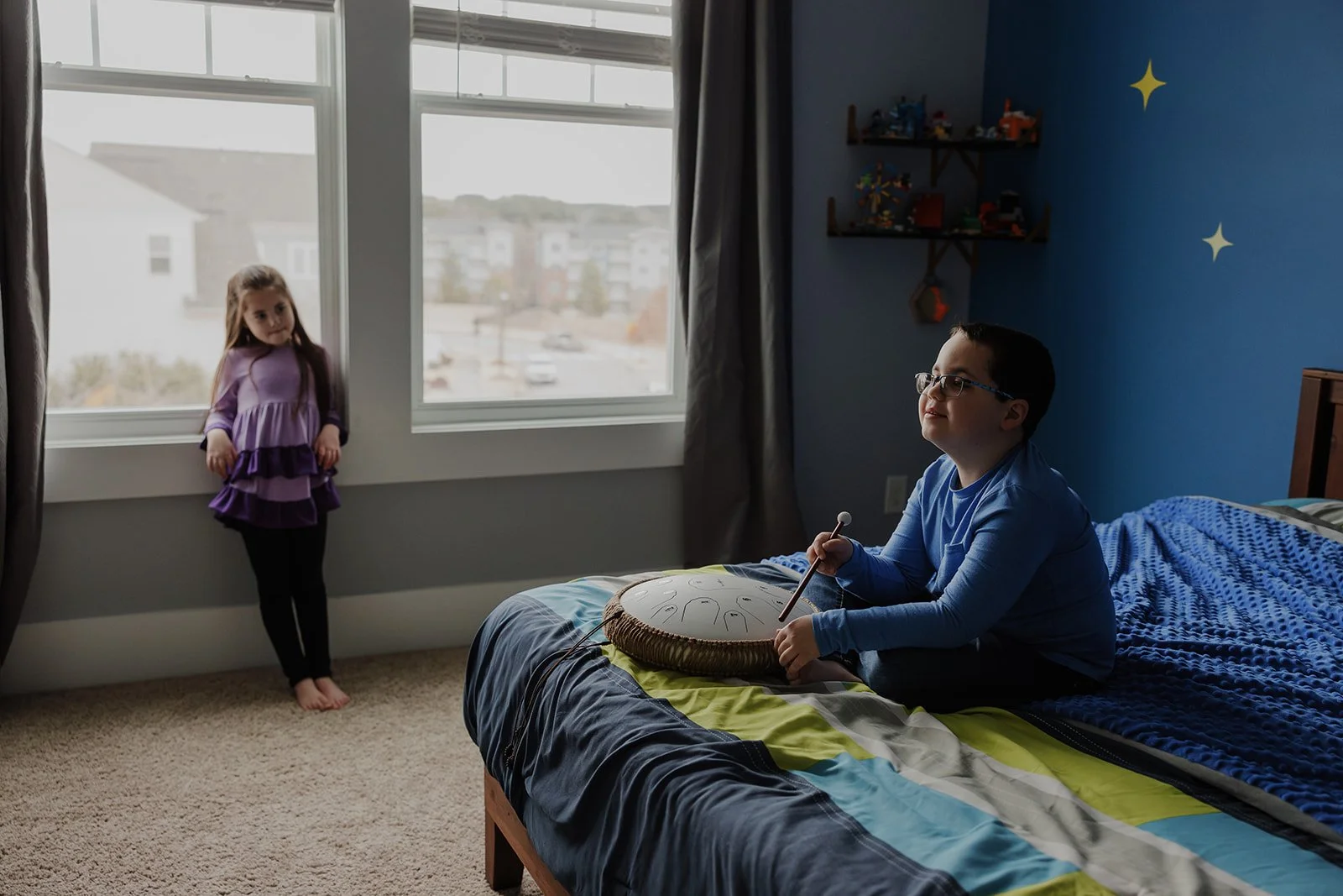 Boy playing his steel drum while sitting on his bed during a relaxed in-home neurodivergent family photography session in Wake Forest, North Carolina.