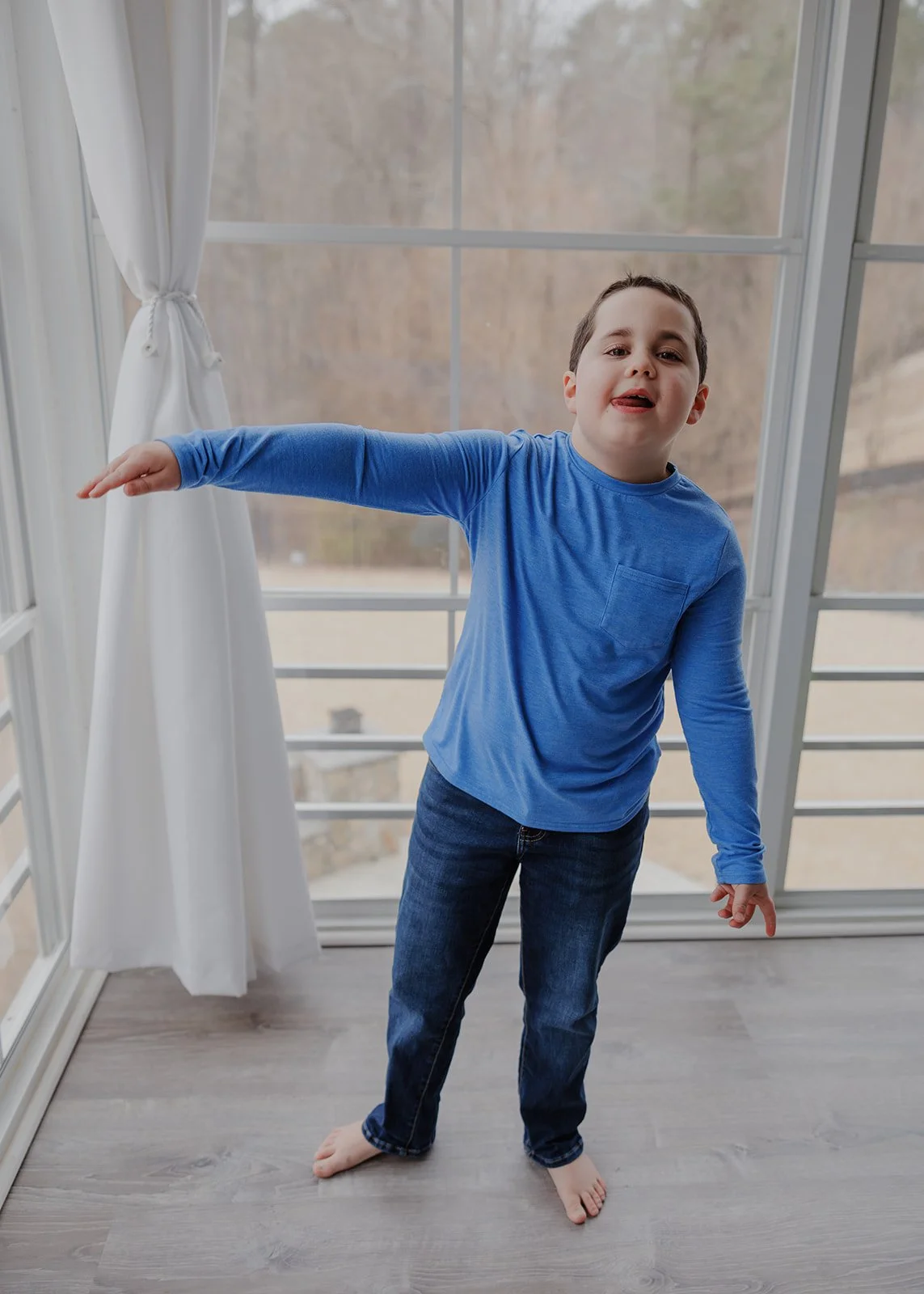 Child standing by a large window during a relaxed in-home family photography session in Wake Forest, North Carolina.