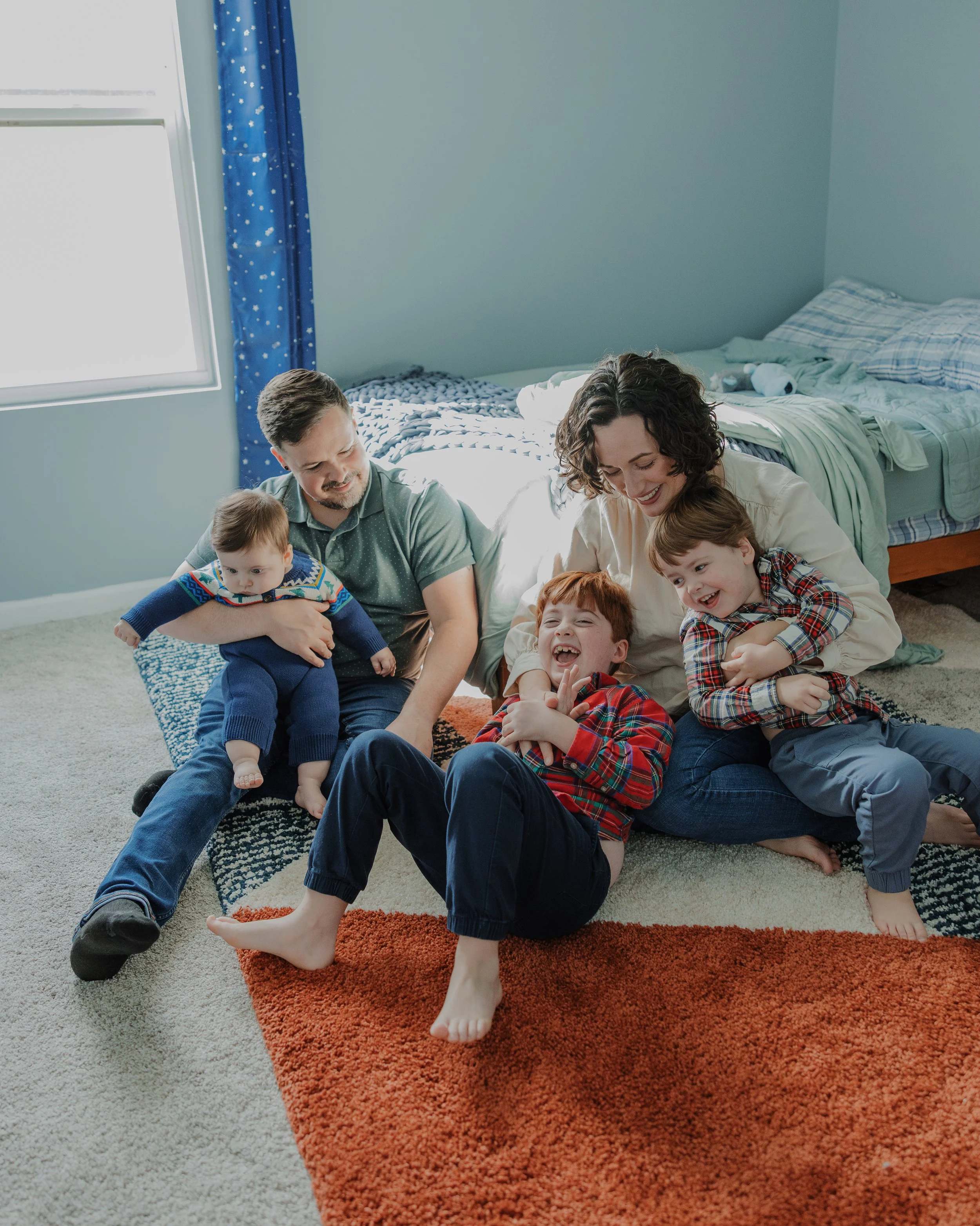 Raleigh in-home family photo session with parents and young children playing together on the floor, capturing joyful, candid moments included in a full family gallery