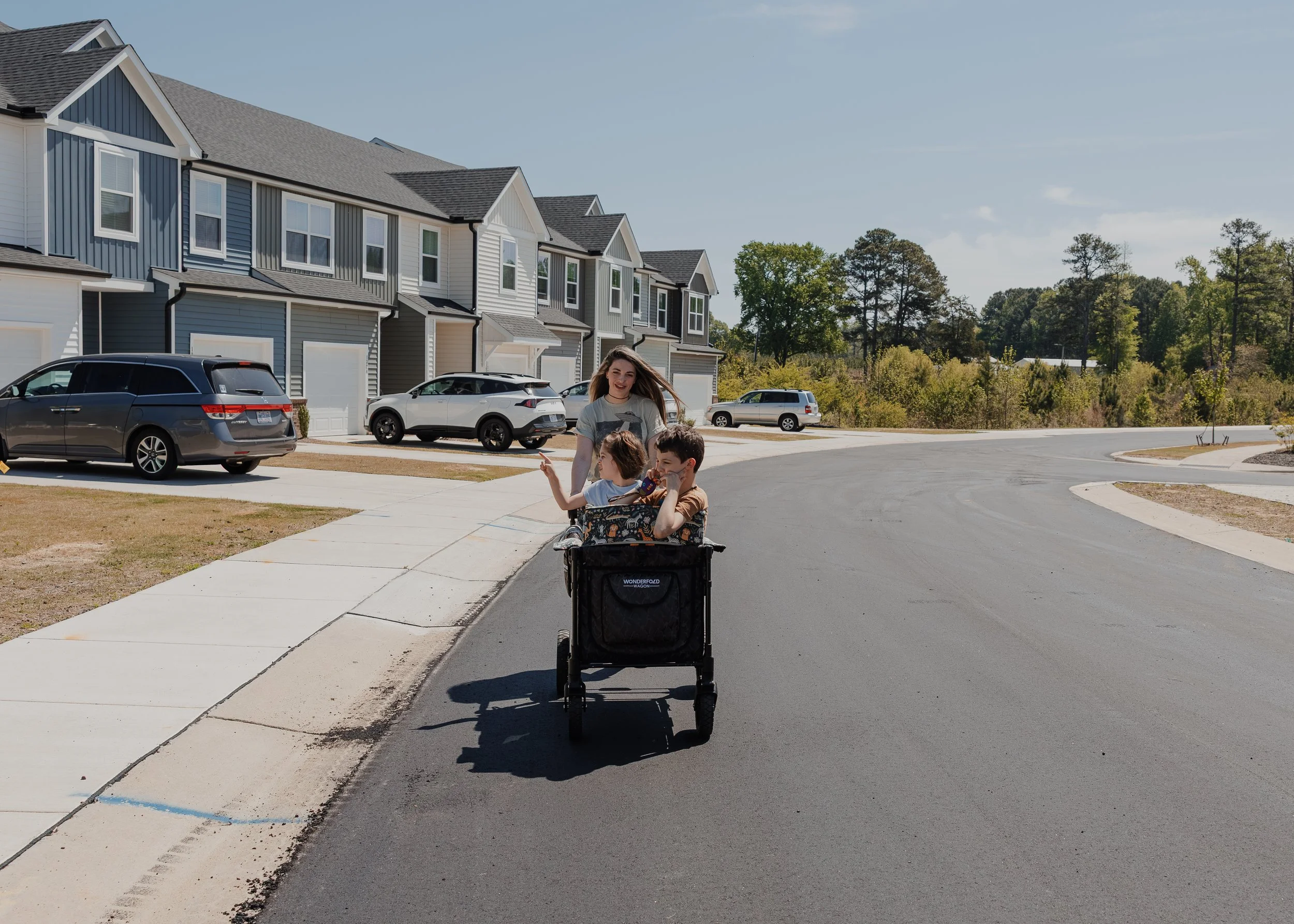 A mother pushes her two autistic children in a WonderFold wagon through their Wake Forest neighborhood during an autism-friendly family photo session.