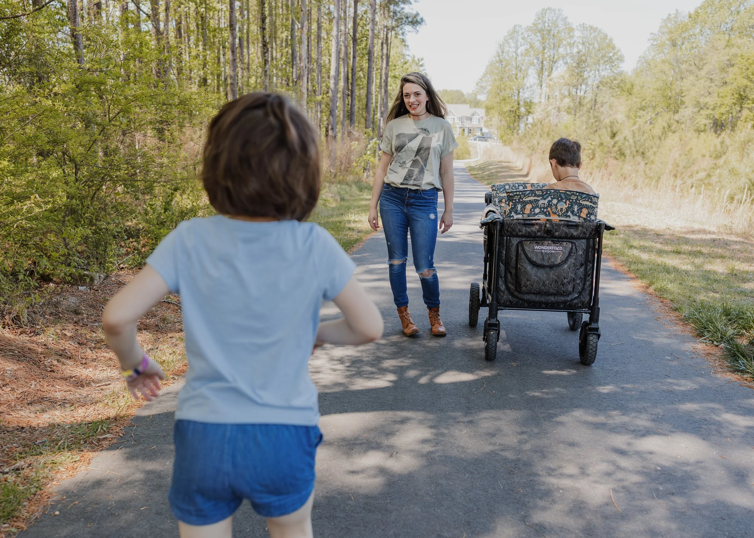 A young autistic girl runs toward her mother on a shaded Wake Forest greenway during a child-led family photo session.