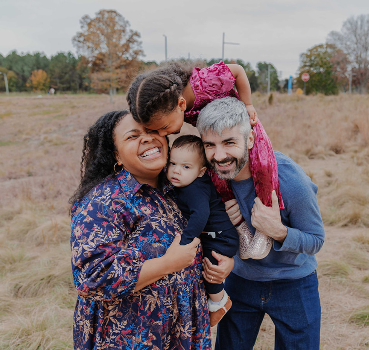 Family with a toddler and baby laugh together during fall family mini photo session at the North Carolina Museum of Art in Raleigh, NC.