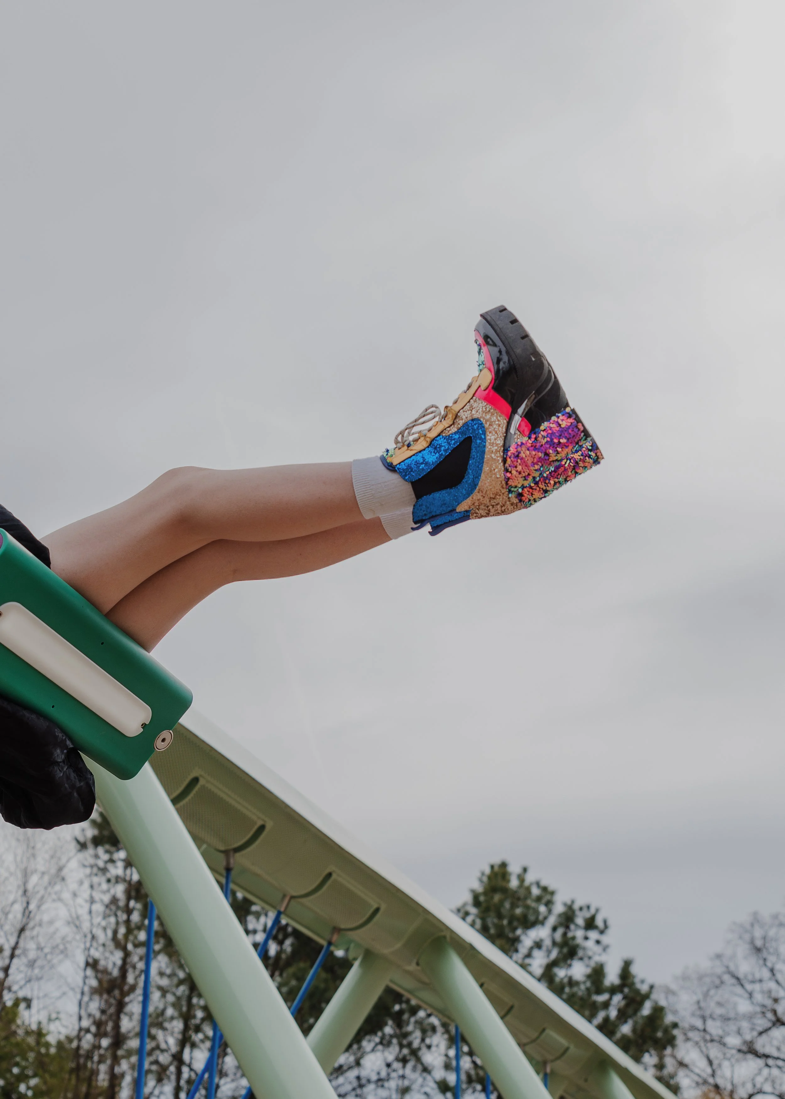 Close-up of child wearing colorful sparkly platform boots on playground equipment during a Raleigh family photo session, highlighting personality and self-expression