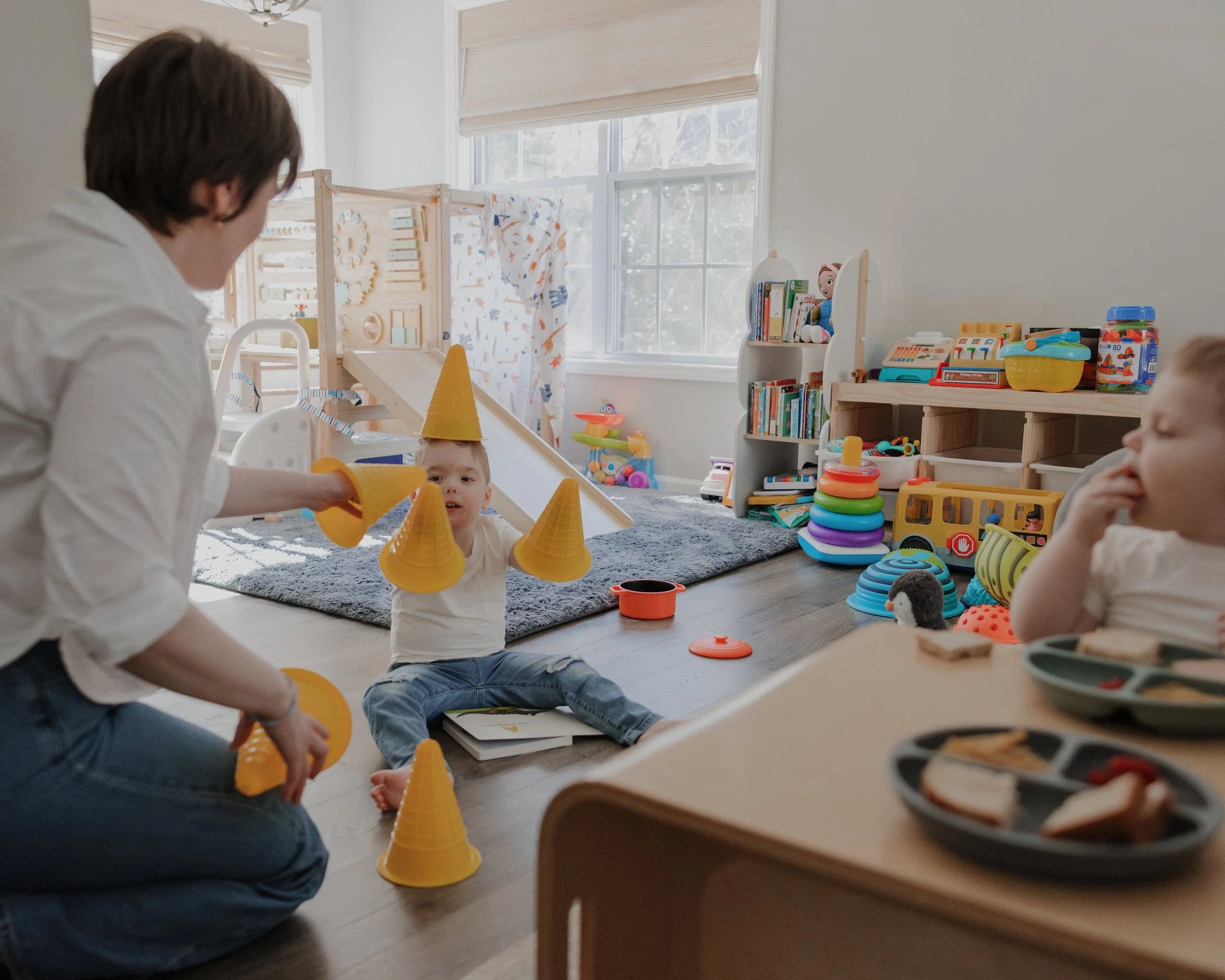 Mother plays with her son using stacking cones on the playroom floor during an inclusive in-home family photography session in Durham, NC for a child with ADNP Syndrome.