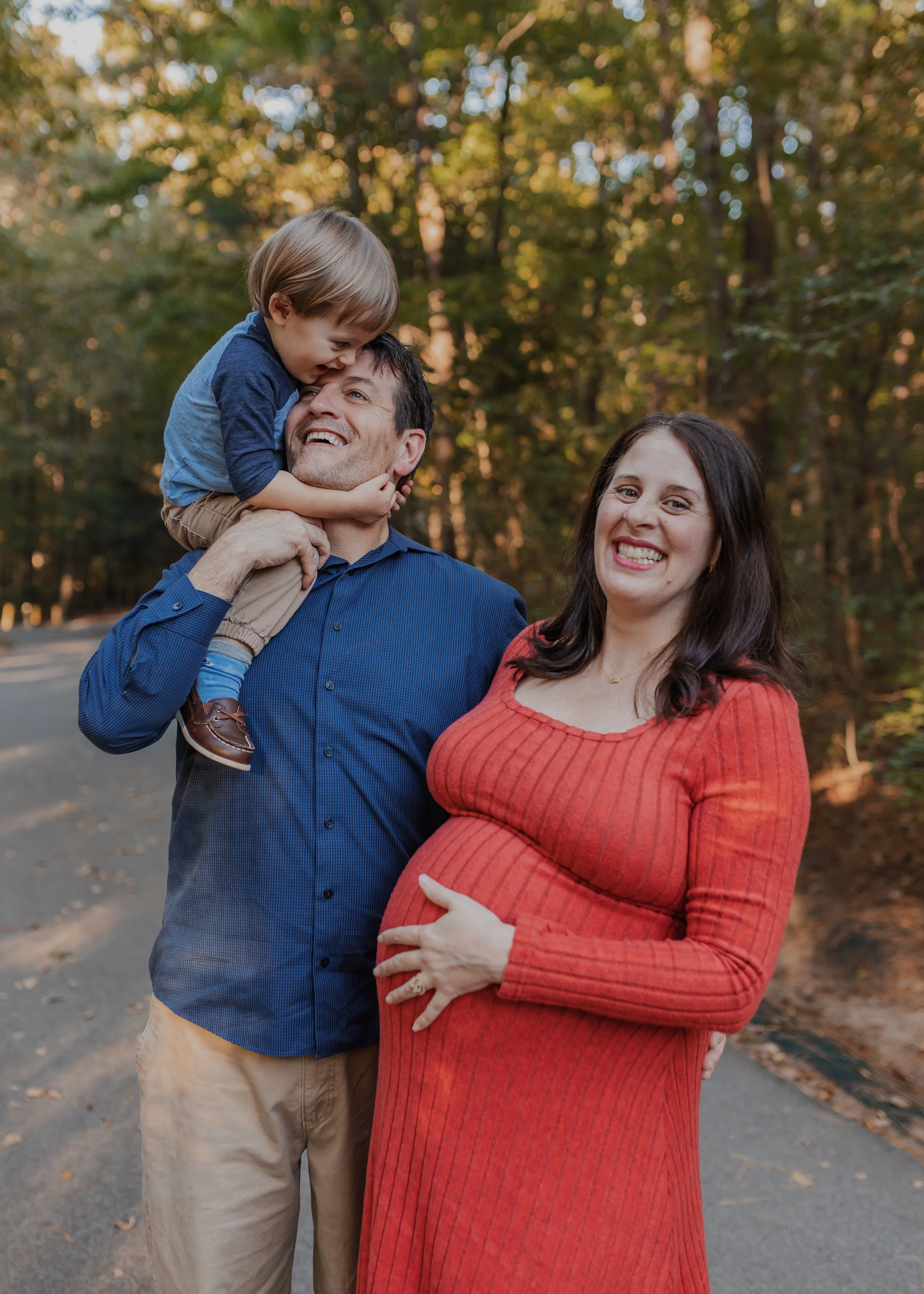Family of 3 laughs during a maternity photo session at Bond Park in Cary.