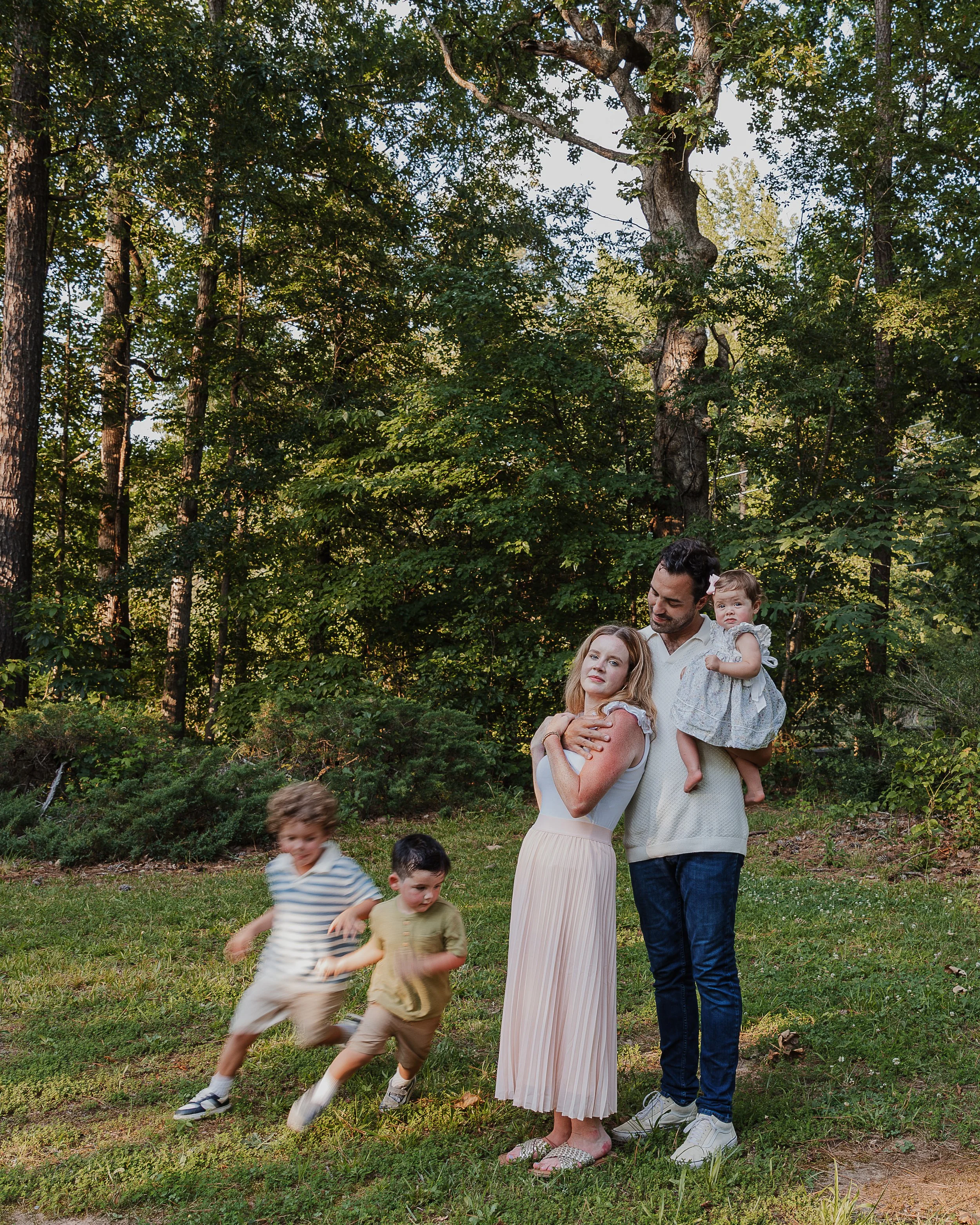 A couple with 3 young kids savor the chaos during a professional family photo session at Yates Mill in Raleigh, NC.