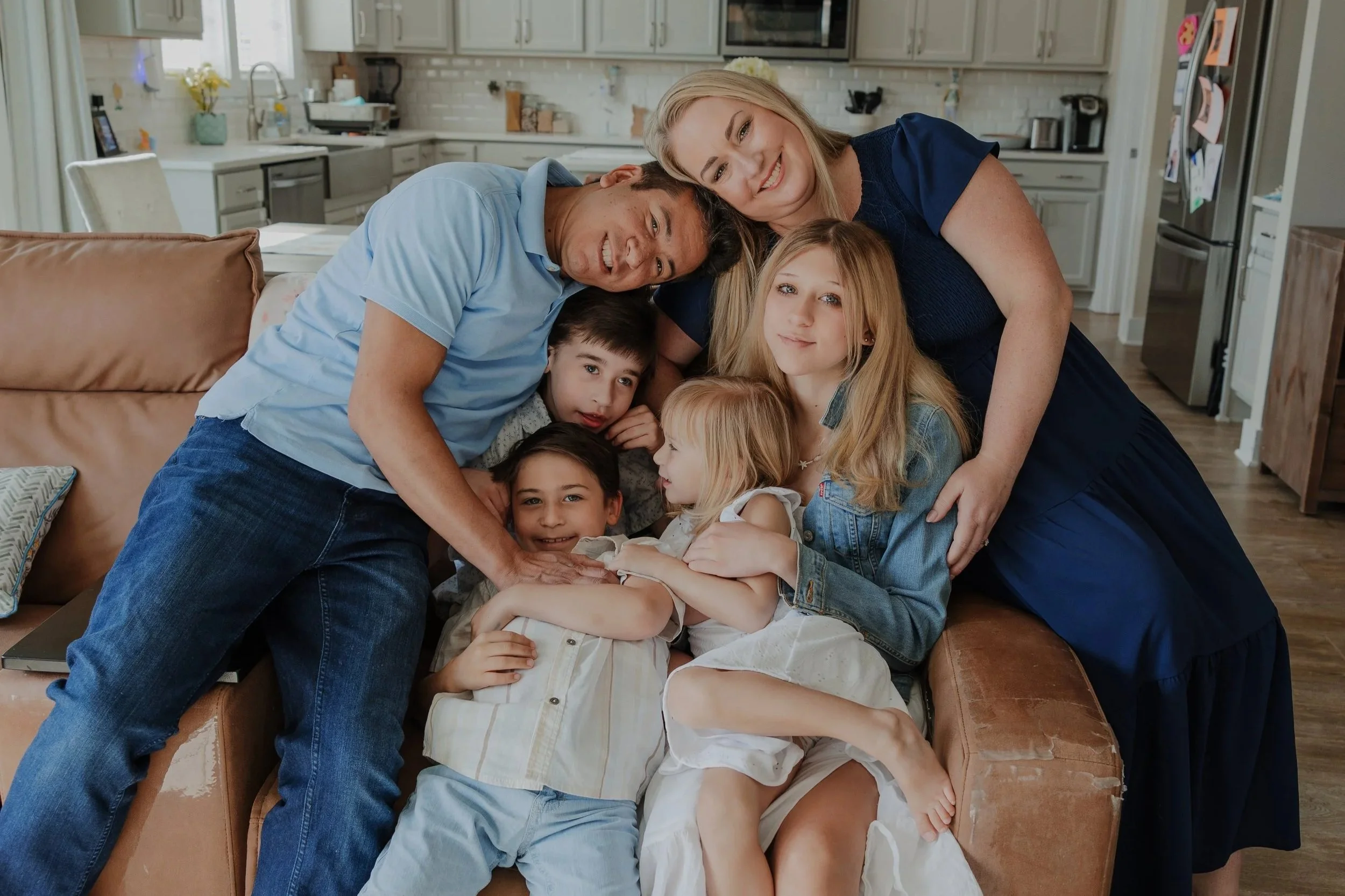 A close-up, child-led family portrait in Knightdale featuring four siblings and parents leaning in close together.