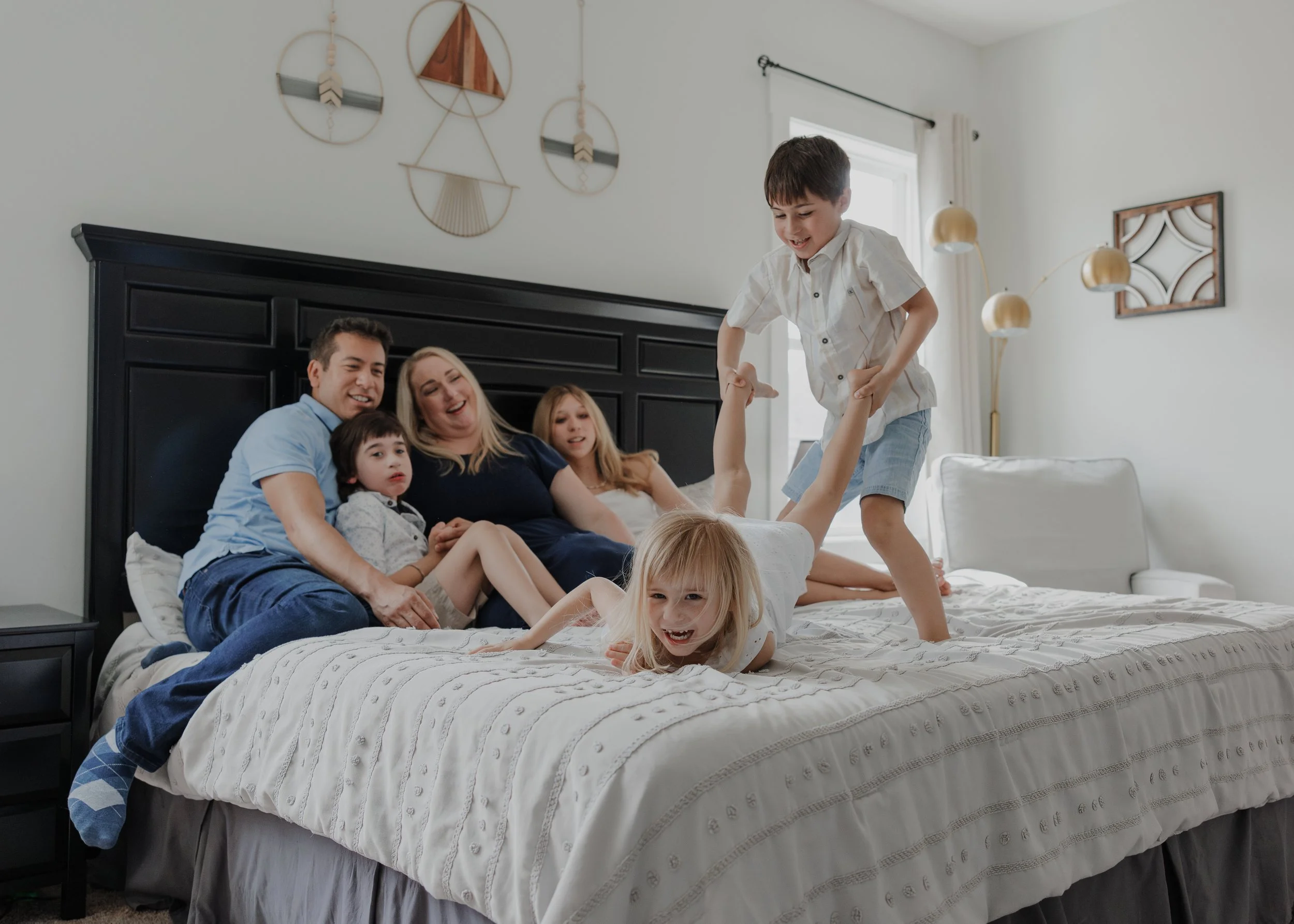 Four children and their parents playing on a bed, capturing the movement and fun of a child-led session in Wendell, NC.