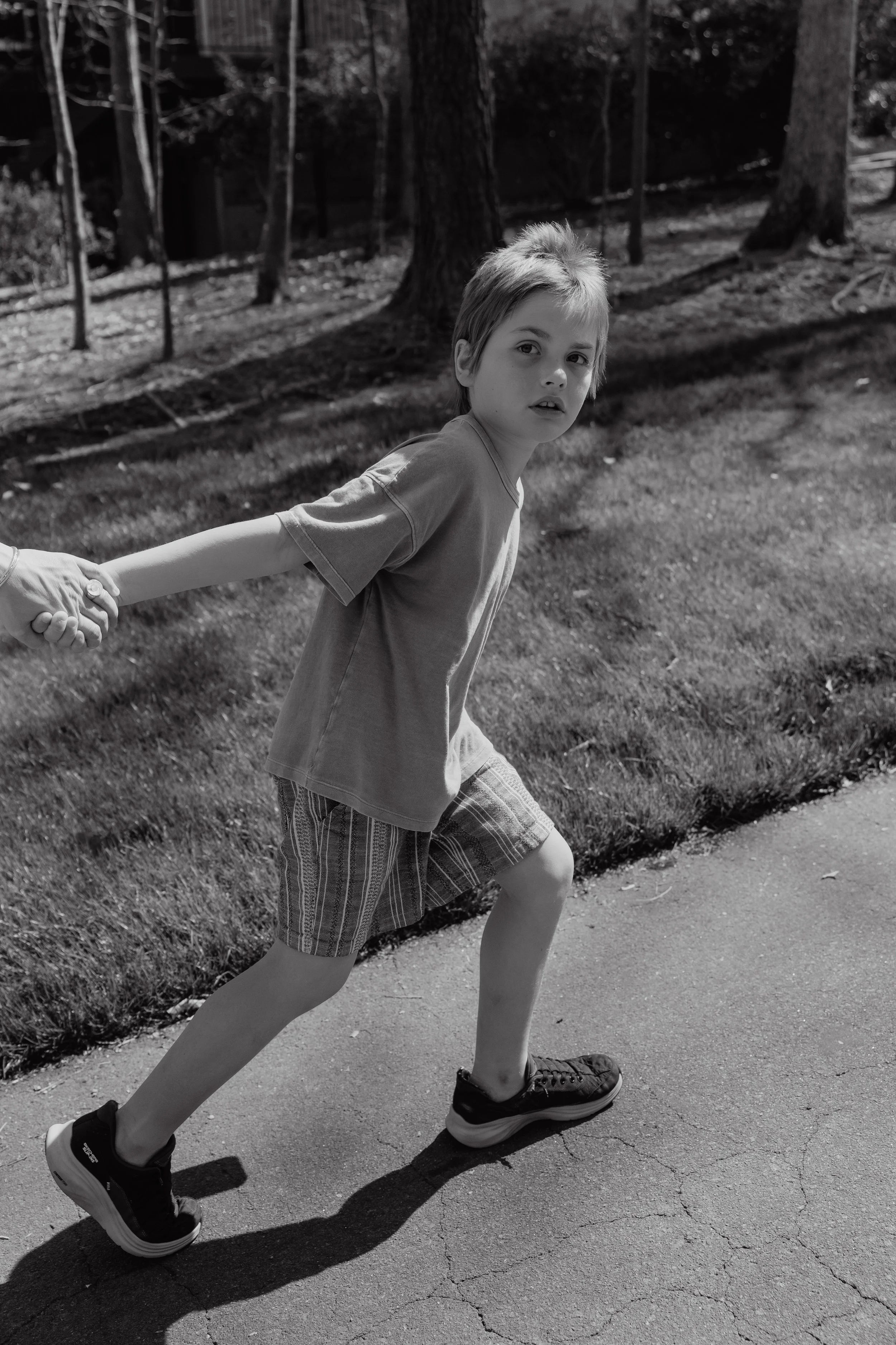 Black and white photo of a child holding a parent's hand while leading the way during a child-led family photography session in Durham, NC.