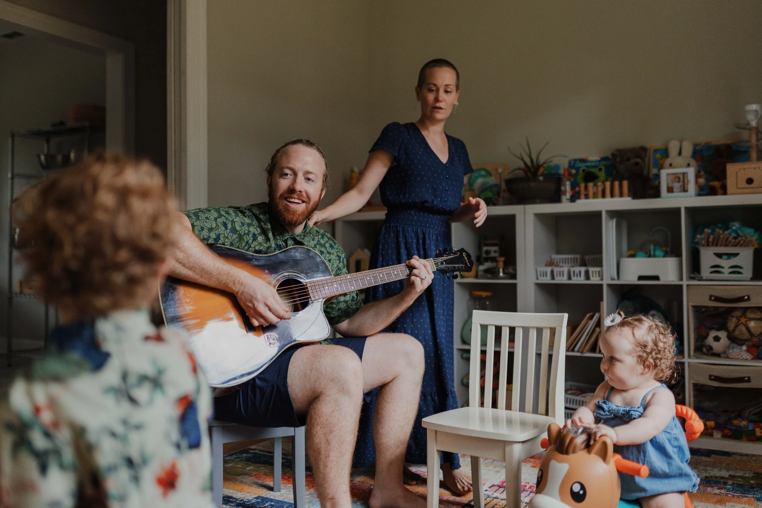 Dad and mom enjoy playing guitar for their young kids during an at home family photo session in Wake Forest, NC.