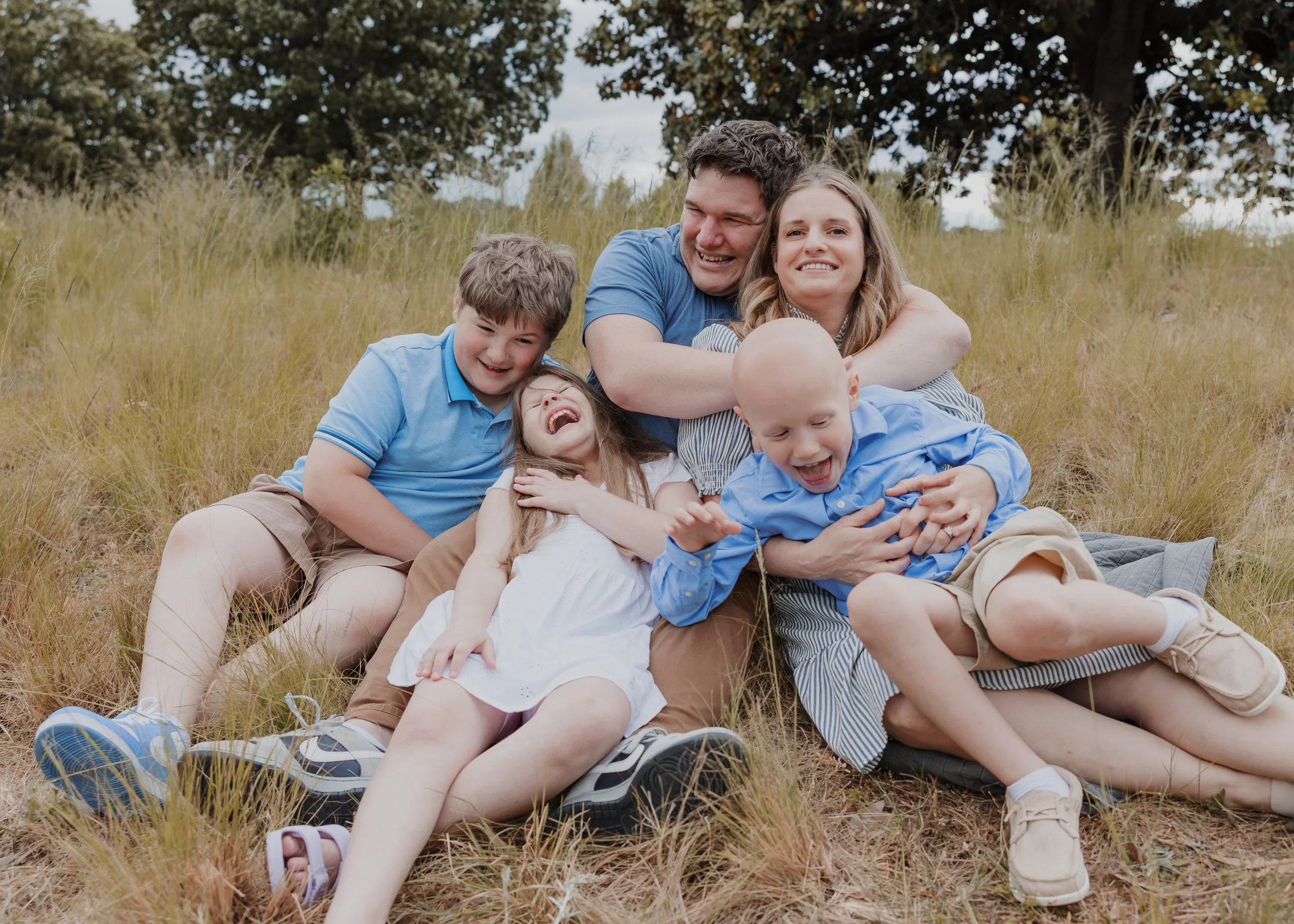 A joyful family of five shares a group hug during a child-led family photo session at the North Carolina Museum of Art in Raleigh, NC.