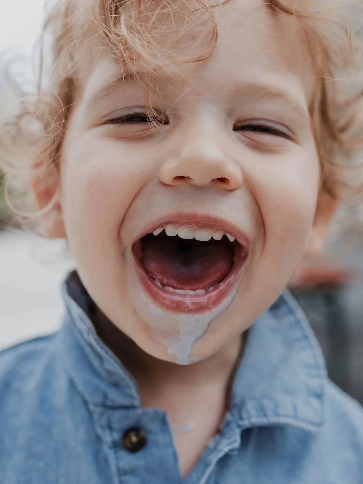 Laughing toddler with melted ice cream on his chin during a Raleigh family outing