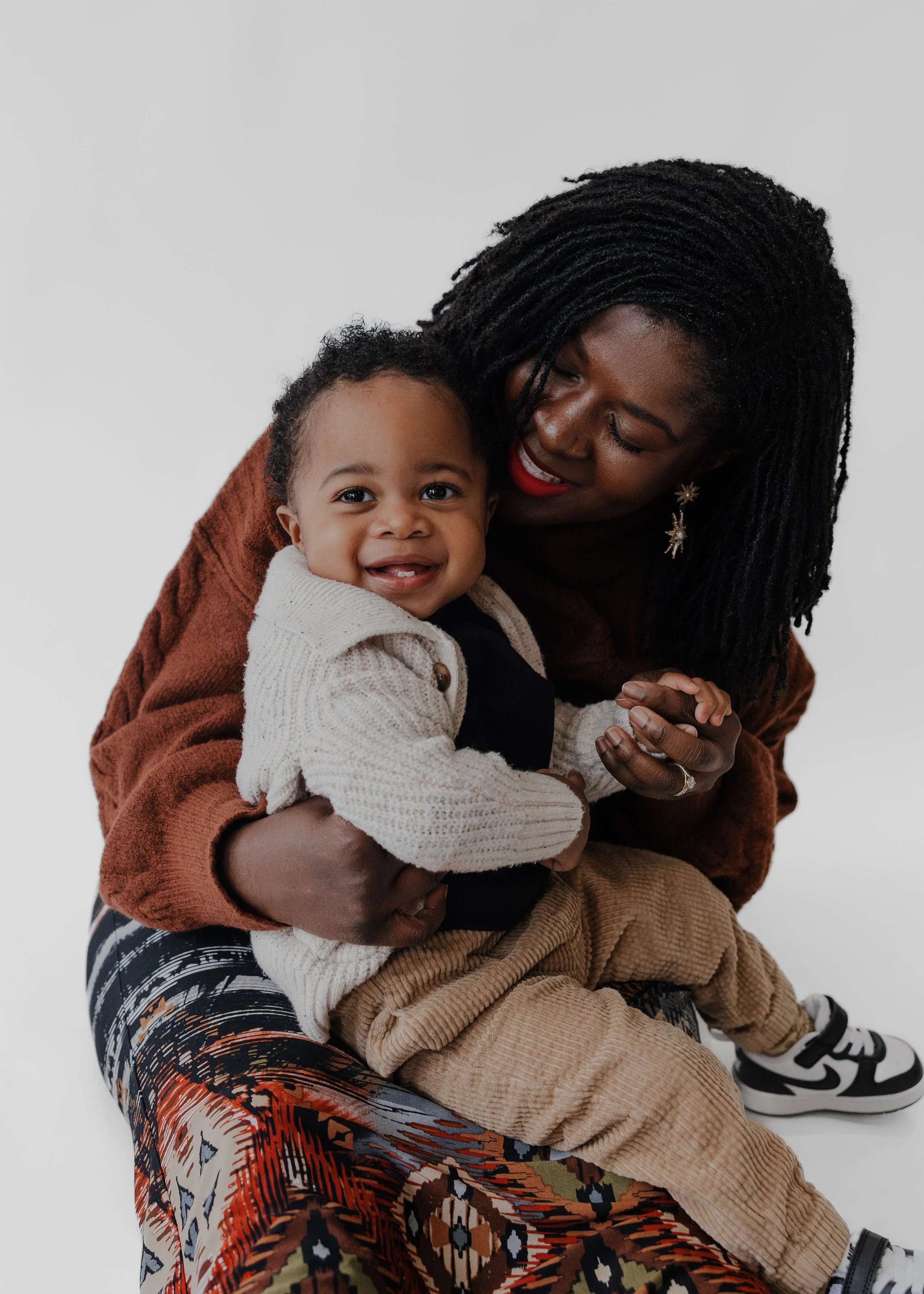 Mom and baby snuggle in front of a white backdrop at a photo studio in Durham, NC.