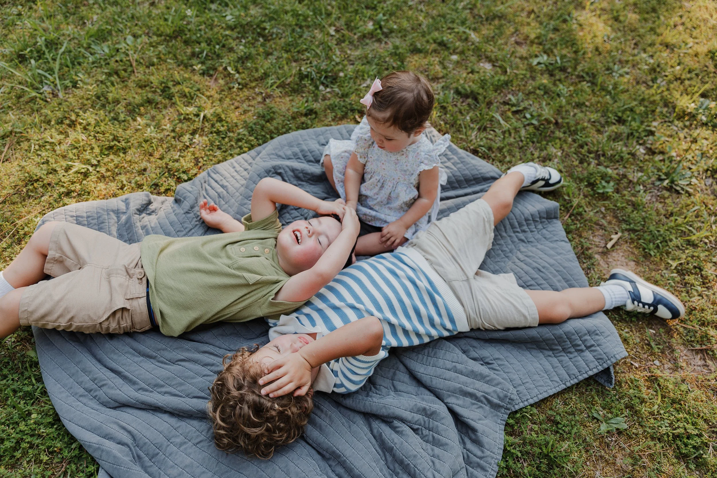 Children taking a break on a blanket in a quiet park, showing how sensory-friendly photo locations in Raleigh provide space for relaxed family photography.