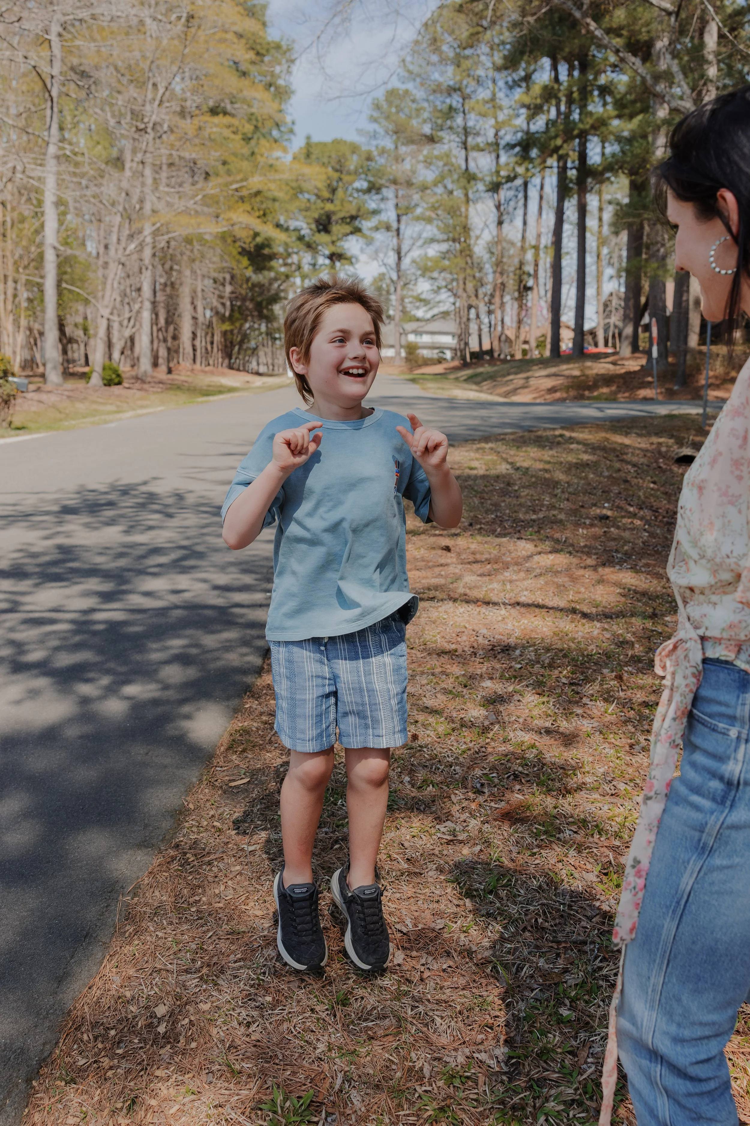 Child with autism and PDA engaging in a happy stimming movement during a family photography session with a neurodivergent friendly photographer in Durham, NC.