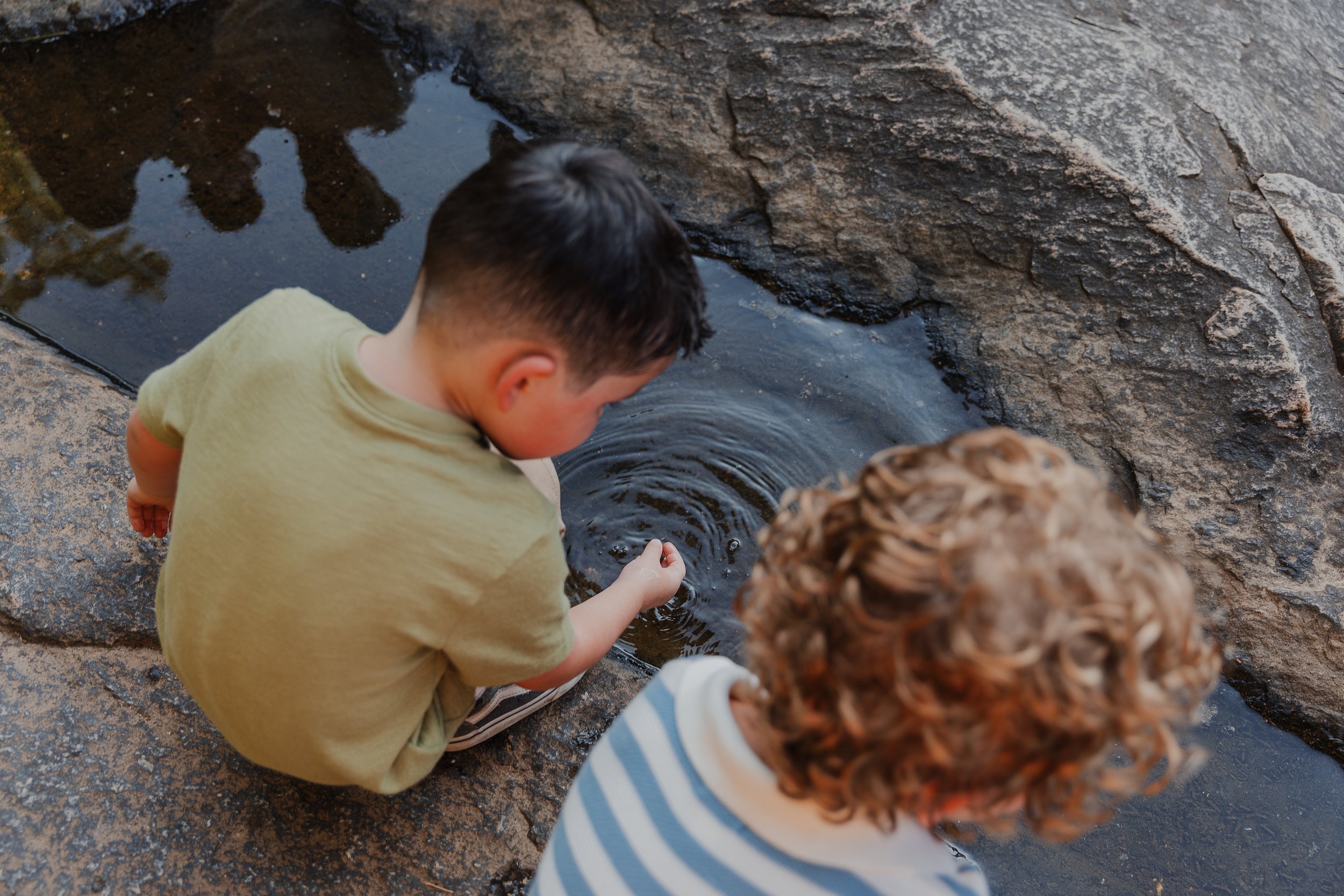 Two young brothers exploring the water together during a candid fall family photo session at Historic Yates Mill County Park in Raleigh, NC.