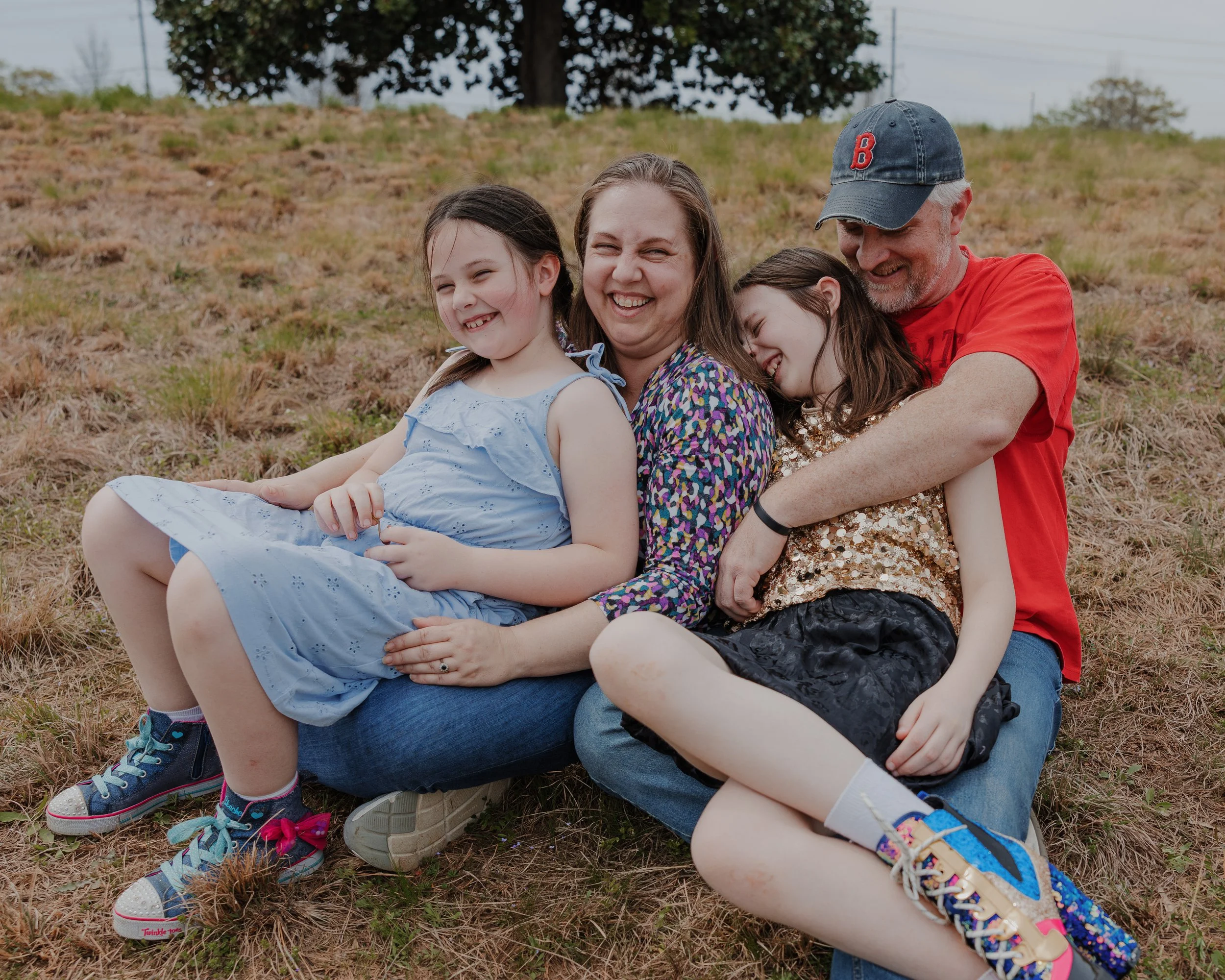 Candid family photo at NCMA in Raleigh with parents and two daughters laughing together, showcasing playful connection and real emotion during a family session