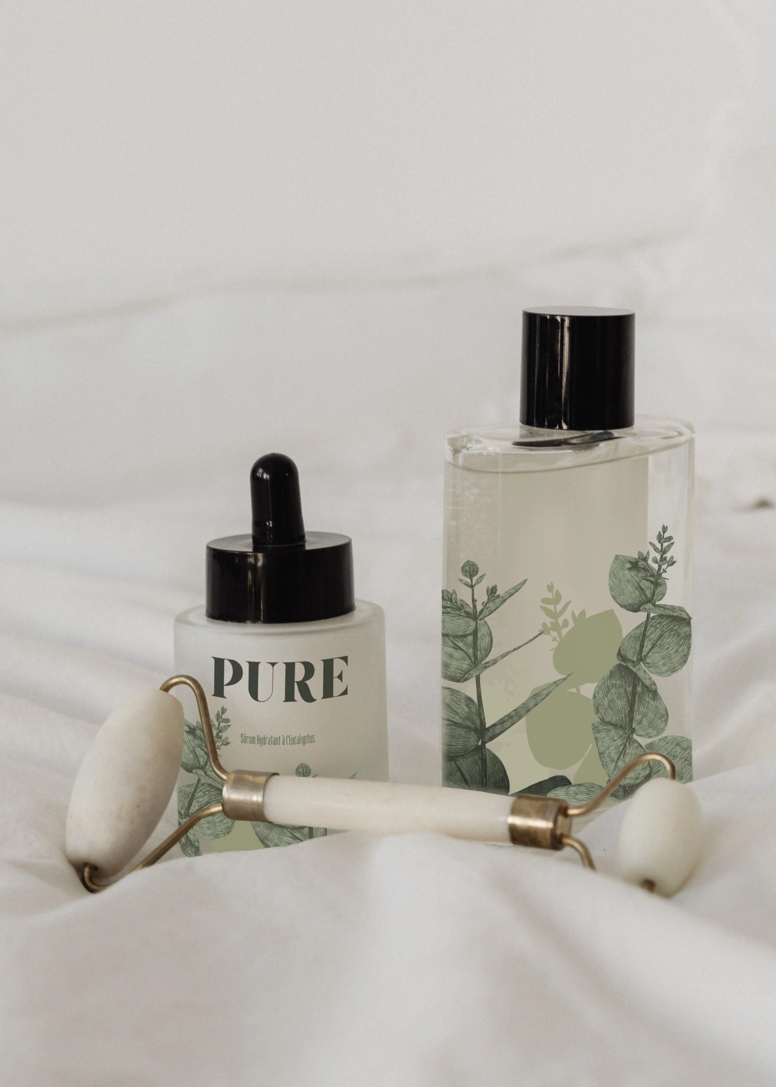 Deux flacons de produits pour la peau avec un rouleau de jade blanc, sur un fond blanc.