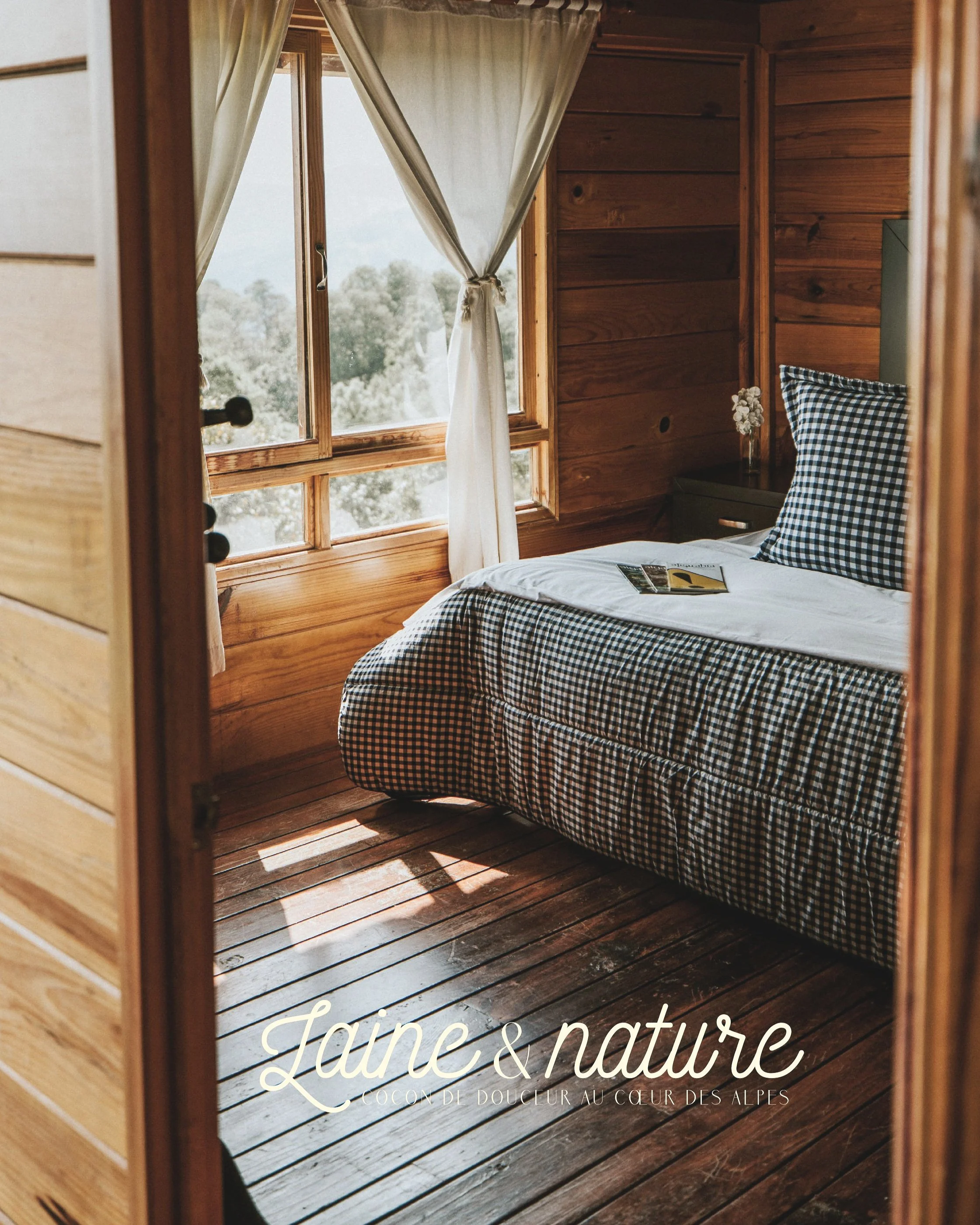 Une chambre en bois avec un lit à une seule place, une fenêtre avec des rideaux blancs, et une table de chevet.