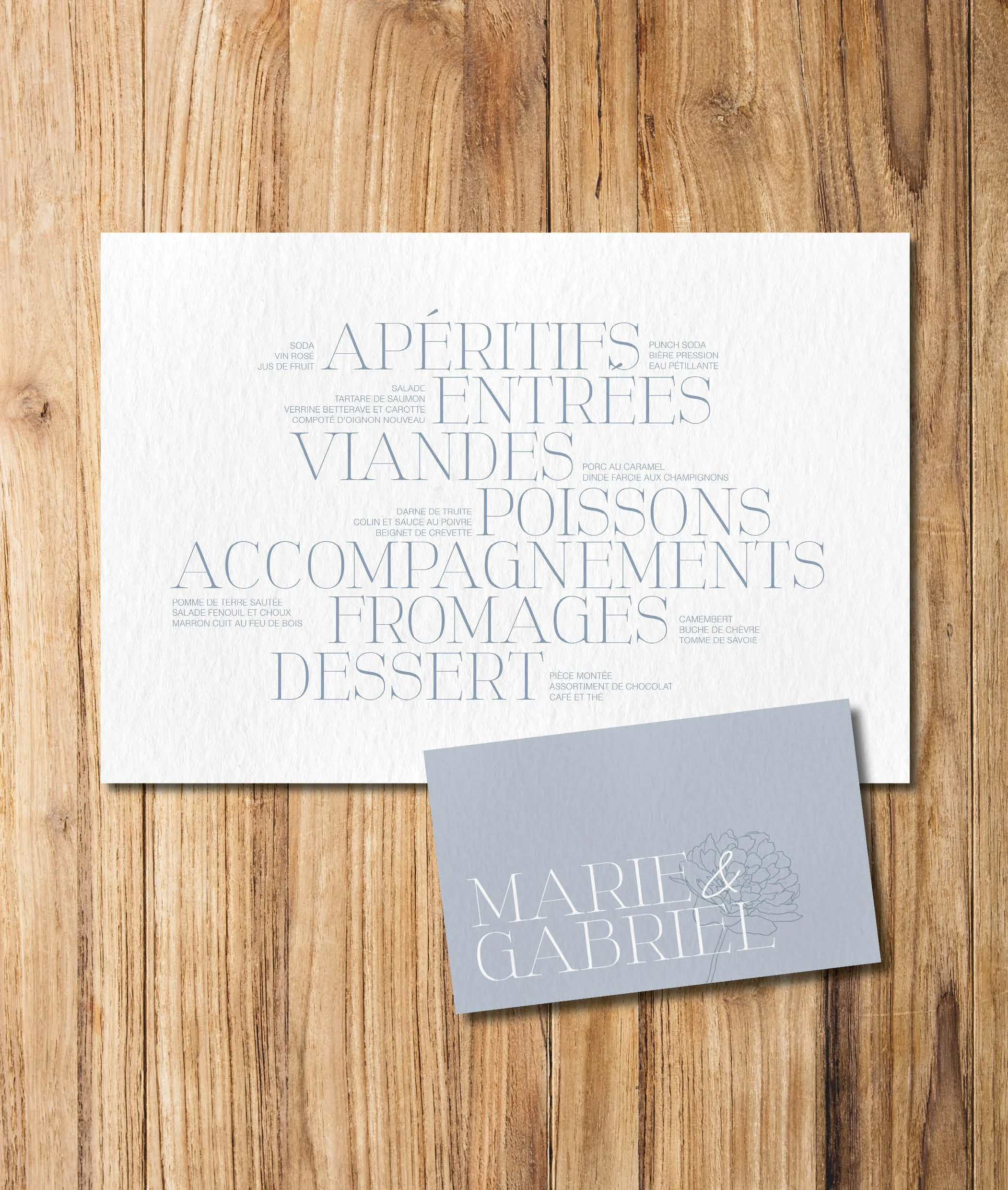 Menu de restaurant sur une table en bois avec deux cartes, l'une avec la liste des plats et l'autre avec les noms Marie et Gabriel.
