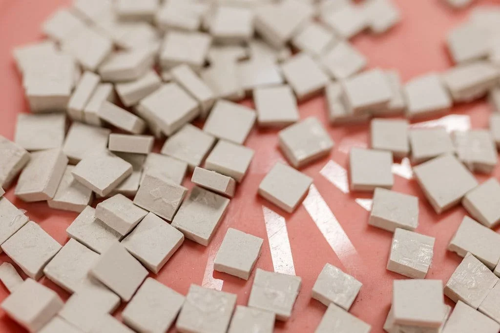 Small white tiles scattered on a pink surface with white arrow symbols.