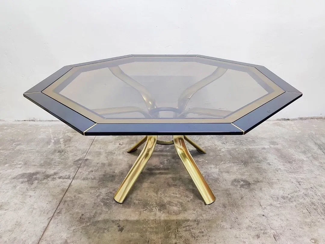 DISPONIBILE 🟢
Tavolo da pranzo Pierre Cardin, anni &rsquo;70.
Struttura scultorea in ottone curvato con base a quattro gambe ramificate.
Piano ottagonale in vetro fum&eacute; con cornice perimetrale decorativa a contrasto, tipica del designer nella 