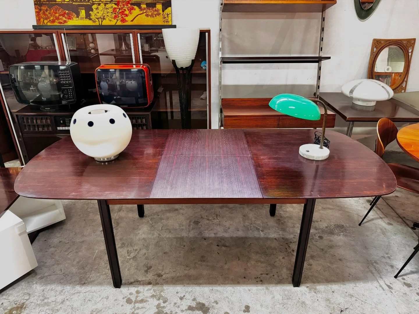 DISPONIBILE 🟢

Tavolo da pranzo estendibile anni &rsquo;60, in legno tinto scuro, proveniente da una sala da pranzo completamente arredata George Coslin.
Piano con angoli stondati e linee morbide tipiche del modernismo europeo, con prolunga centrale