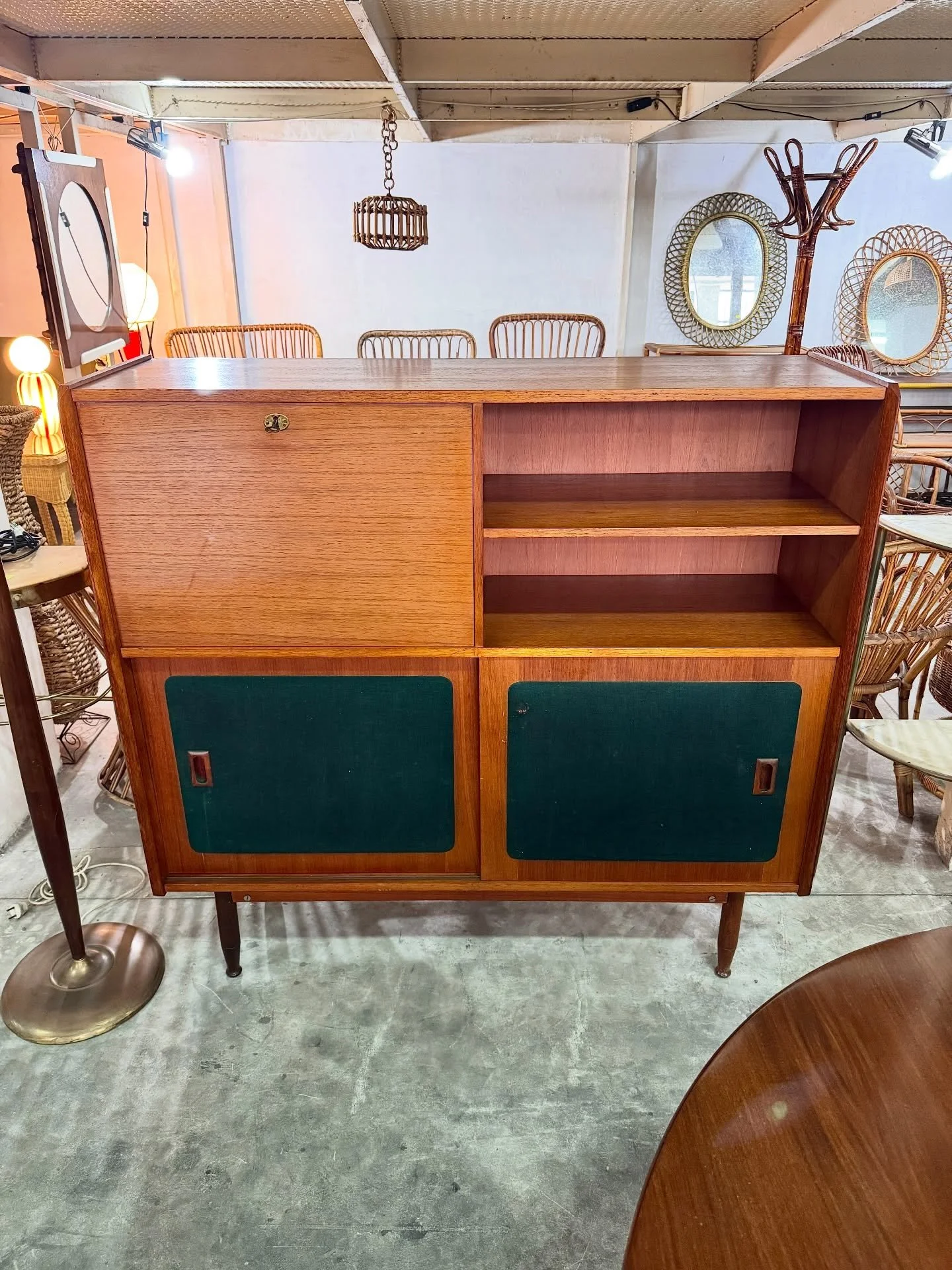 DISPONIBILE 🟢

Highboard in legno con pannelli verdi, ante scorrevoli e ribalta, anni &rsquo;60.

Struttura in legno impiallacciato teak con piedini slanciati. Composizione asimmetrica con vano a giorno laterale, anta superiore a ribalta con serratu