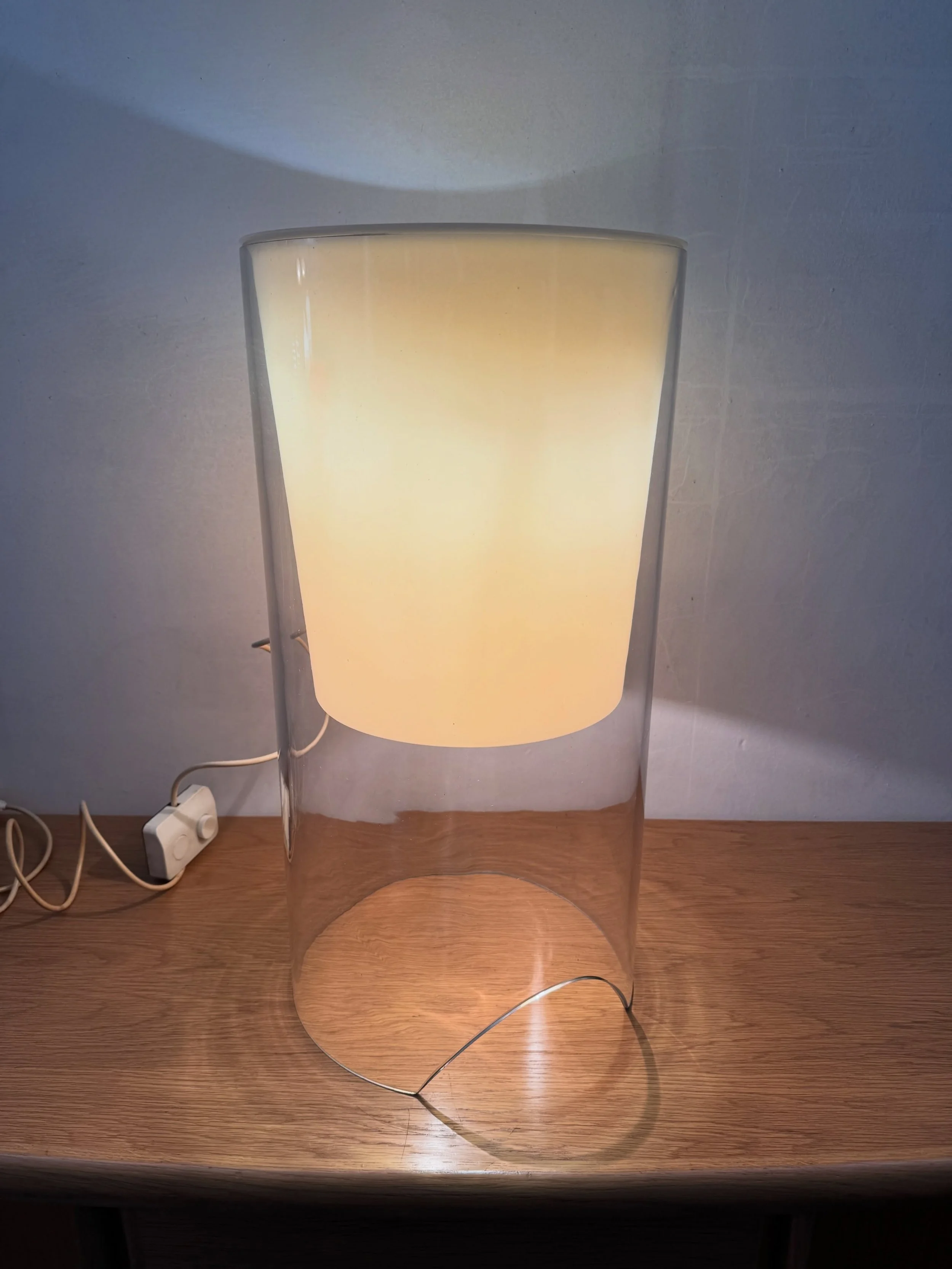 DISPONIBILE - emporium900.com 🟢

Lampada da tavolo &ldquo;Aoy&rdquo;, Achille Castiglioni per Flos, produzione 1971.

Cilindro in vetro trasparente aperto alla base, diffusore interno conico in vetro color avorio con bulbo a vista su stelo metallico
