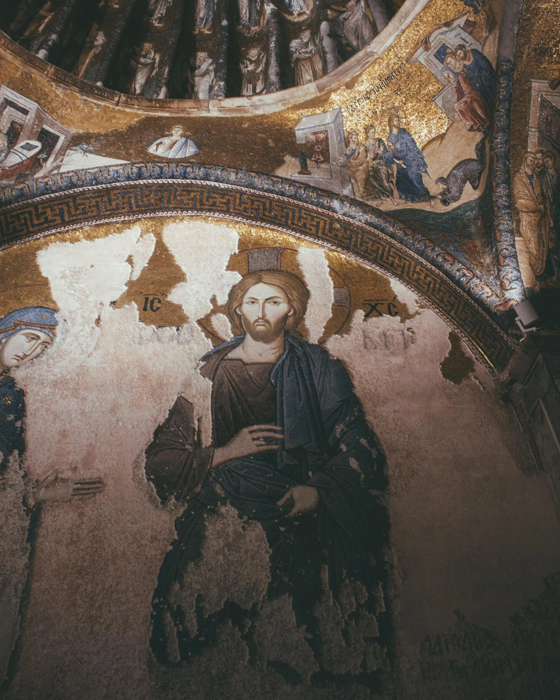 Mosaic of Jesus Christ with a halo, wearing dark robes, set against a golden background in a church.