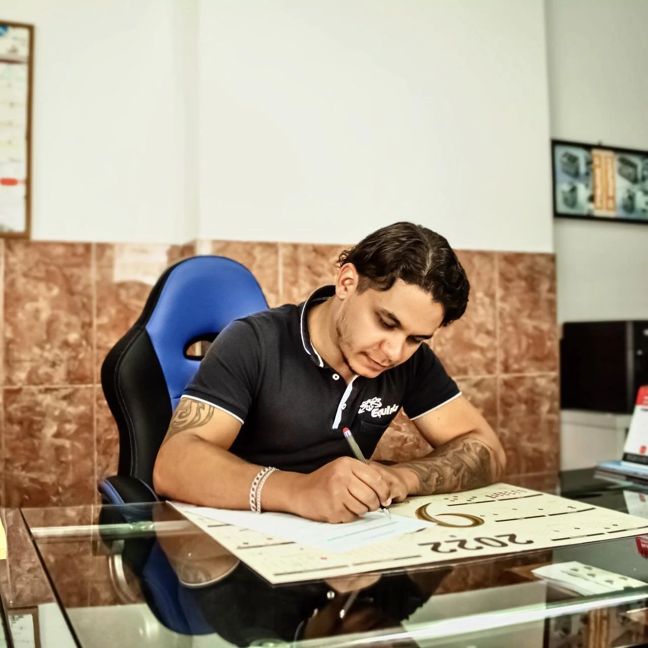 Jovem mulher com cabelo castanho claro, vestindo uma jaqueta amarela, camiseta preta e jeans, posição de perfil, em frente a porta vermelha e paredes amarelas.