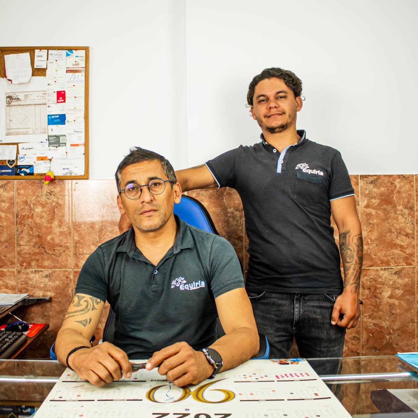 Mulher com boné e roupa preta, sentada em um banco, colocando objetos em uma mochila de cor laranja com a palavra 'RAINS' escrita nela, em um ambiente ao ar livre.