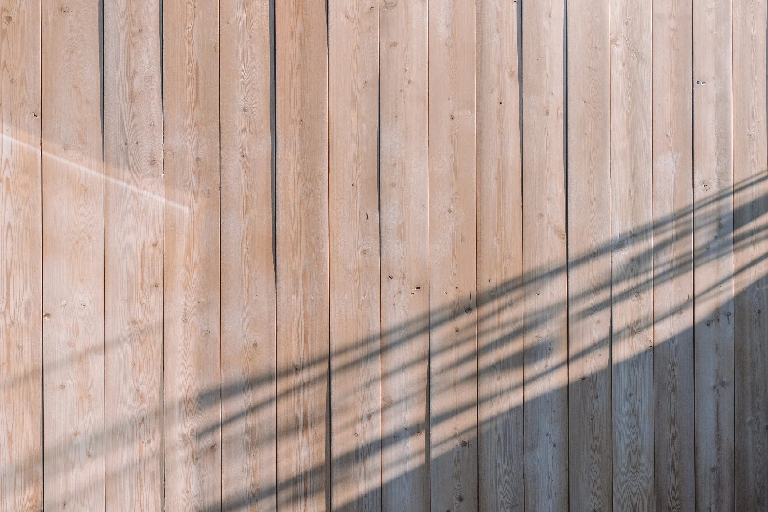 Close-up view of a wooden fence with a shadow cast across it.
