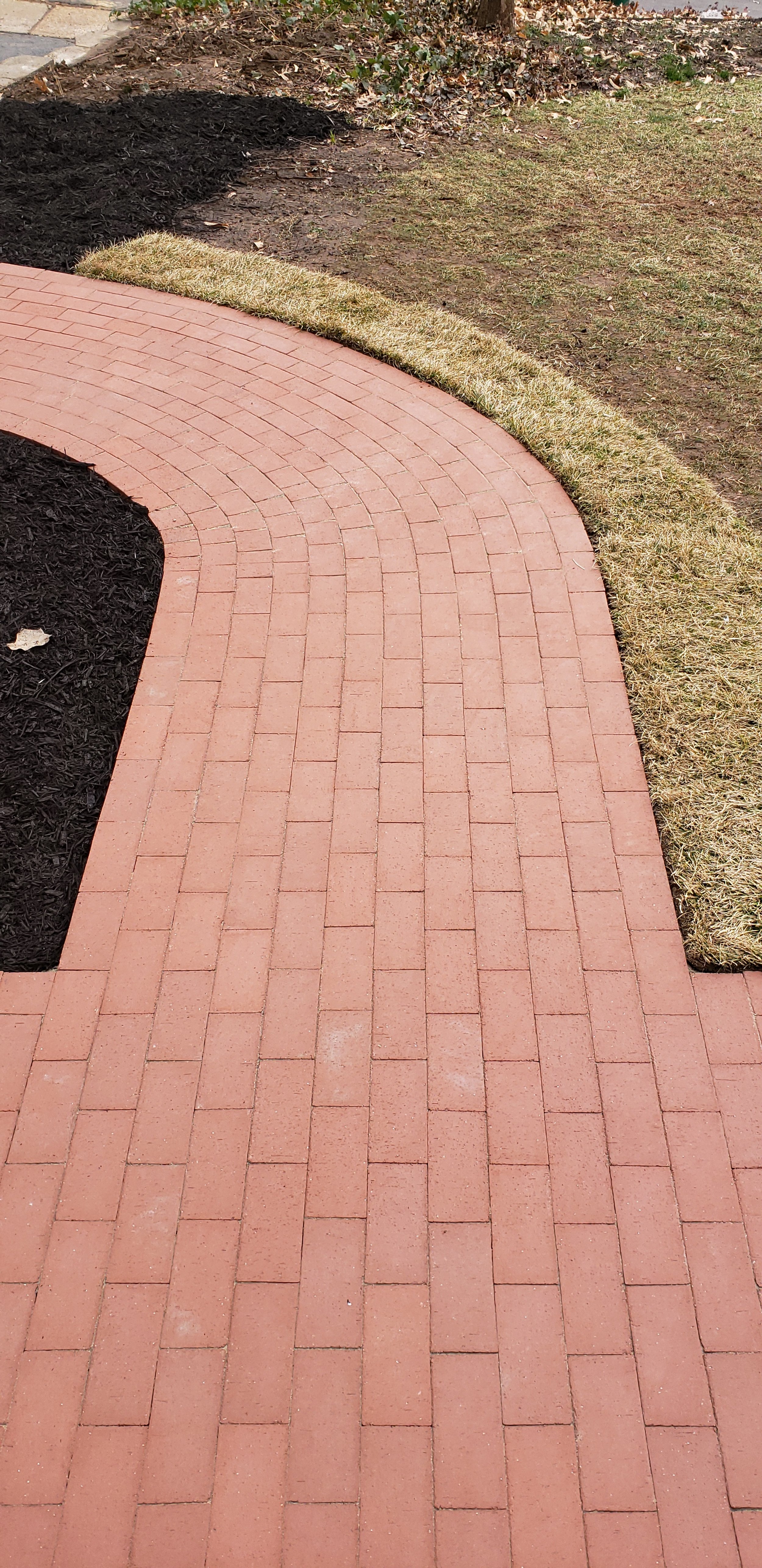 Red brick walkway with grass and mulch on either side