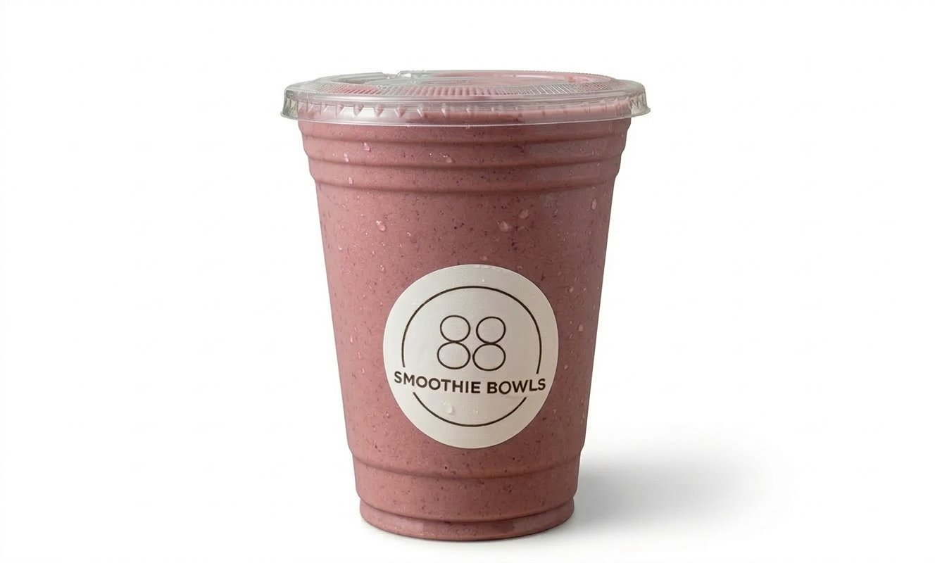 A pink smoothie in a clear plastic cup with a clear plastic lid and a white label that says "88 Smoothie Bowls."