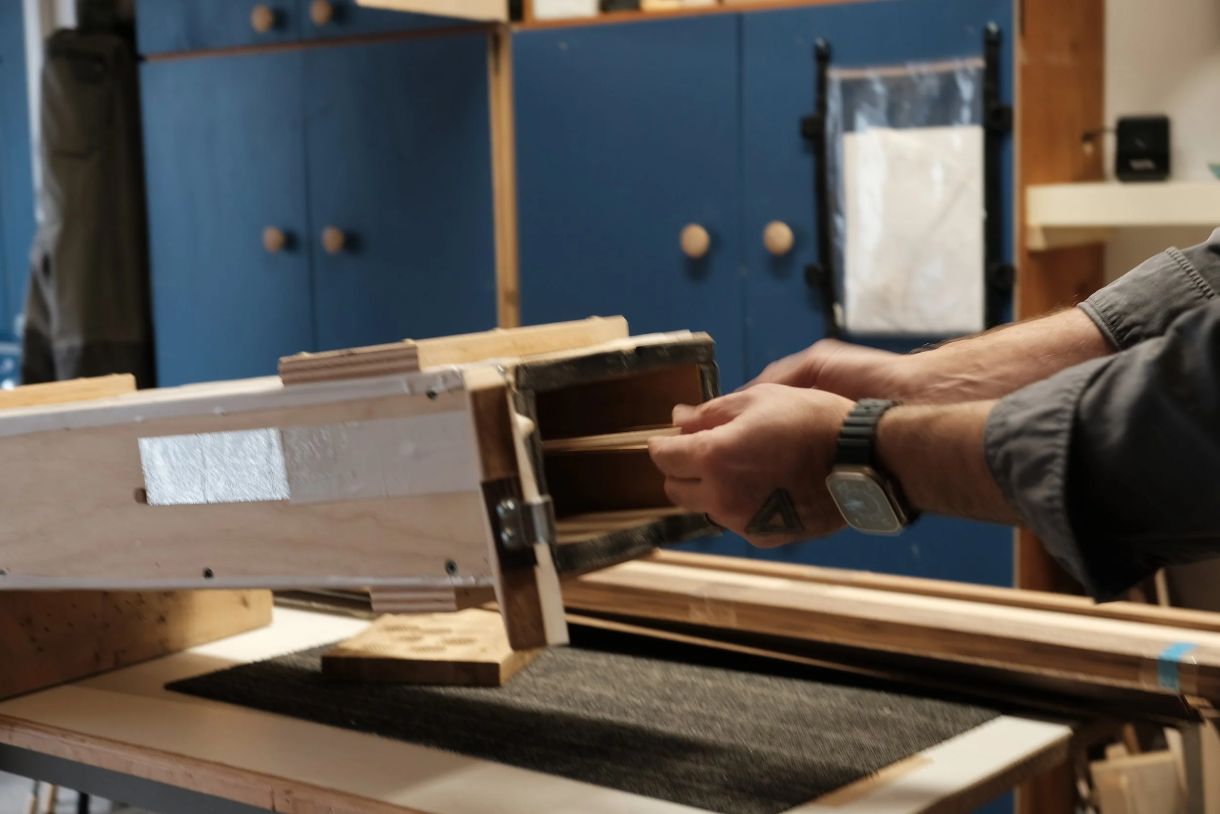 Person steam bending wood strips in a workshop.