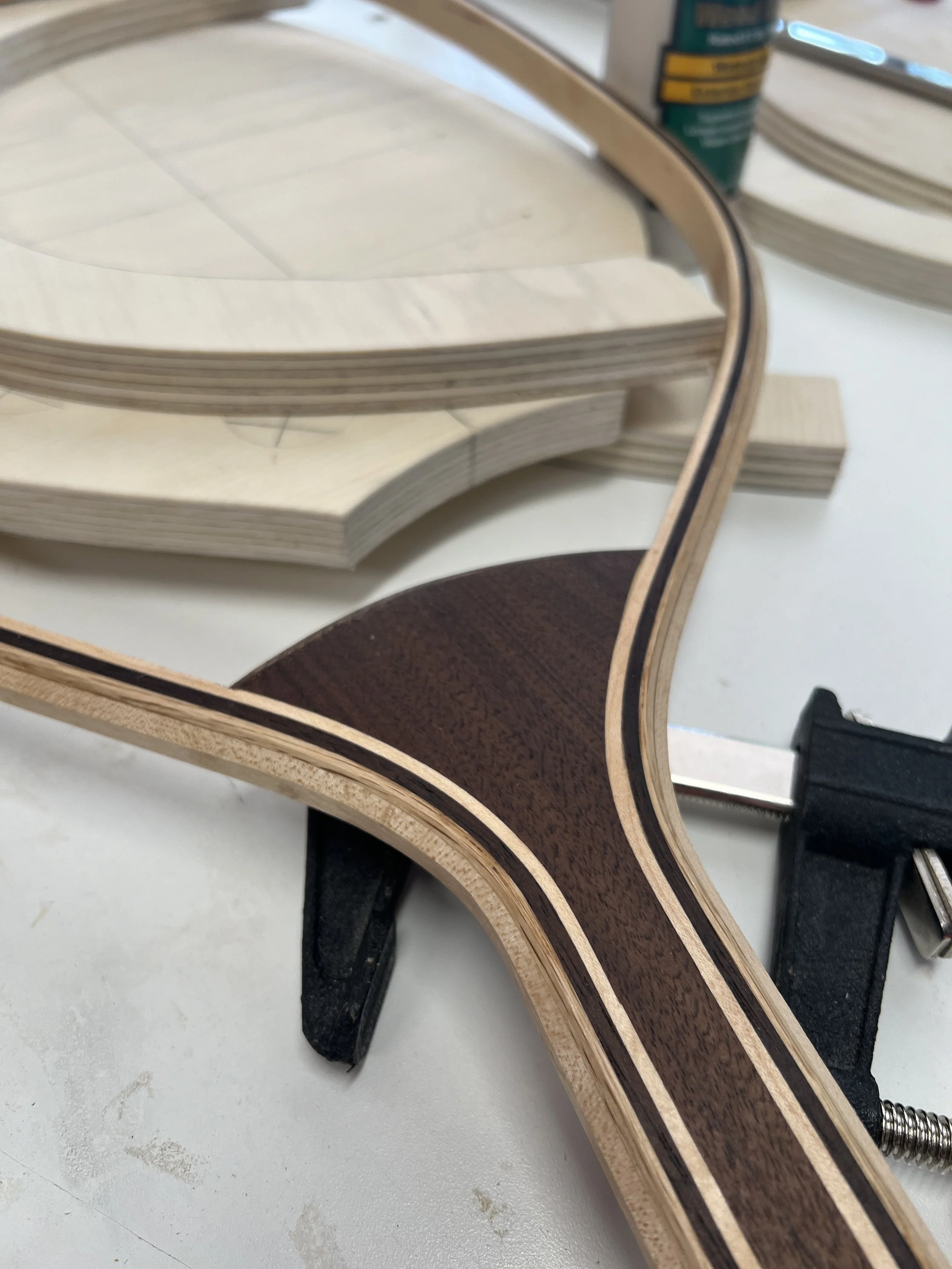 Close-up of layered wooden components clamped together during a woodworking project.