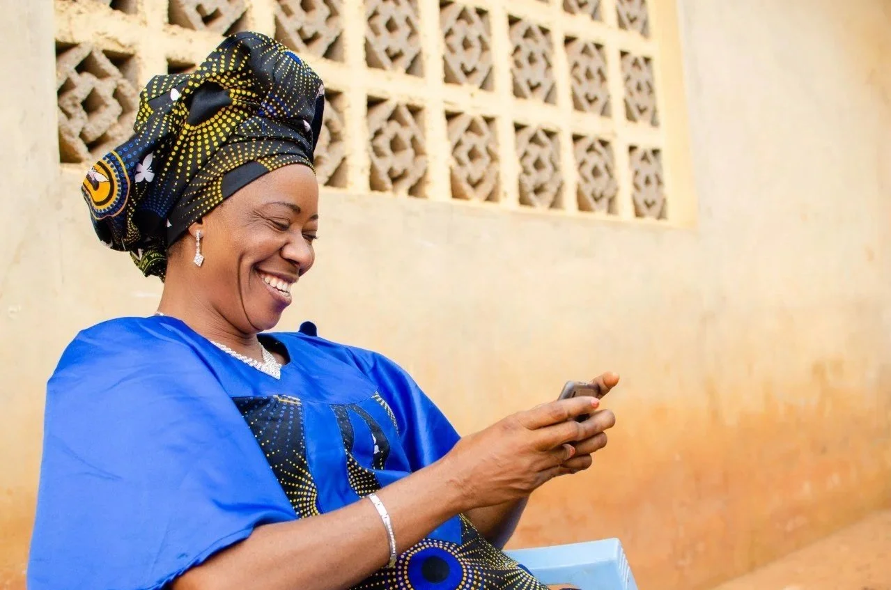 smiling woman wearing traditional african attire looking at phone