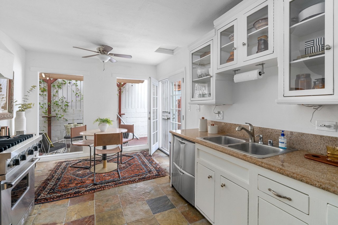 A cozy eat-in kitchen with a chef's range that opens to an airy, sunlit walkway.